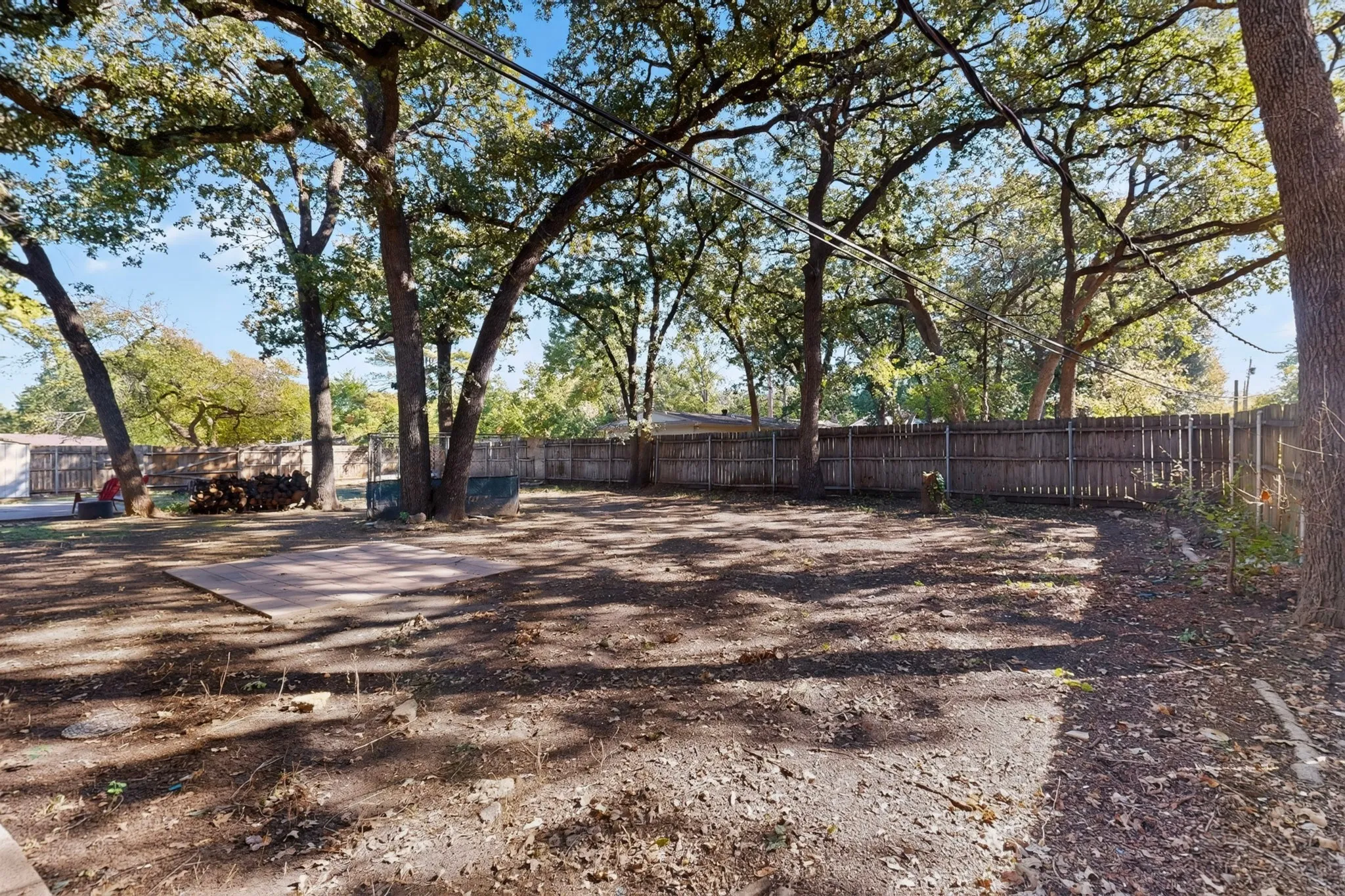 Expansive fenced yard featuring mature trees and a concrete patio