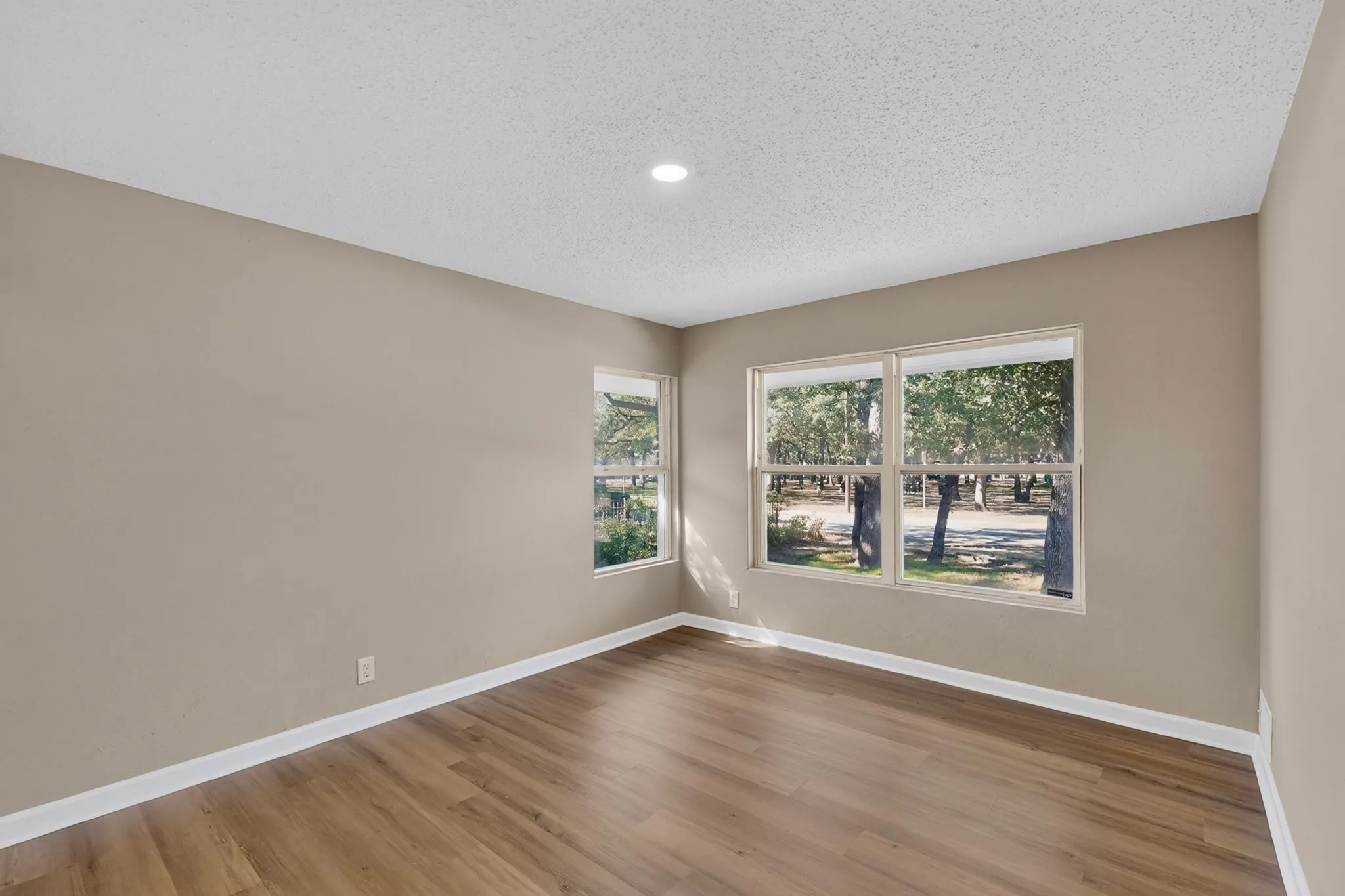 Wood-finish flooring, recessed ceiling light, multiple windows, and neutral wall paint