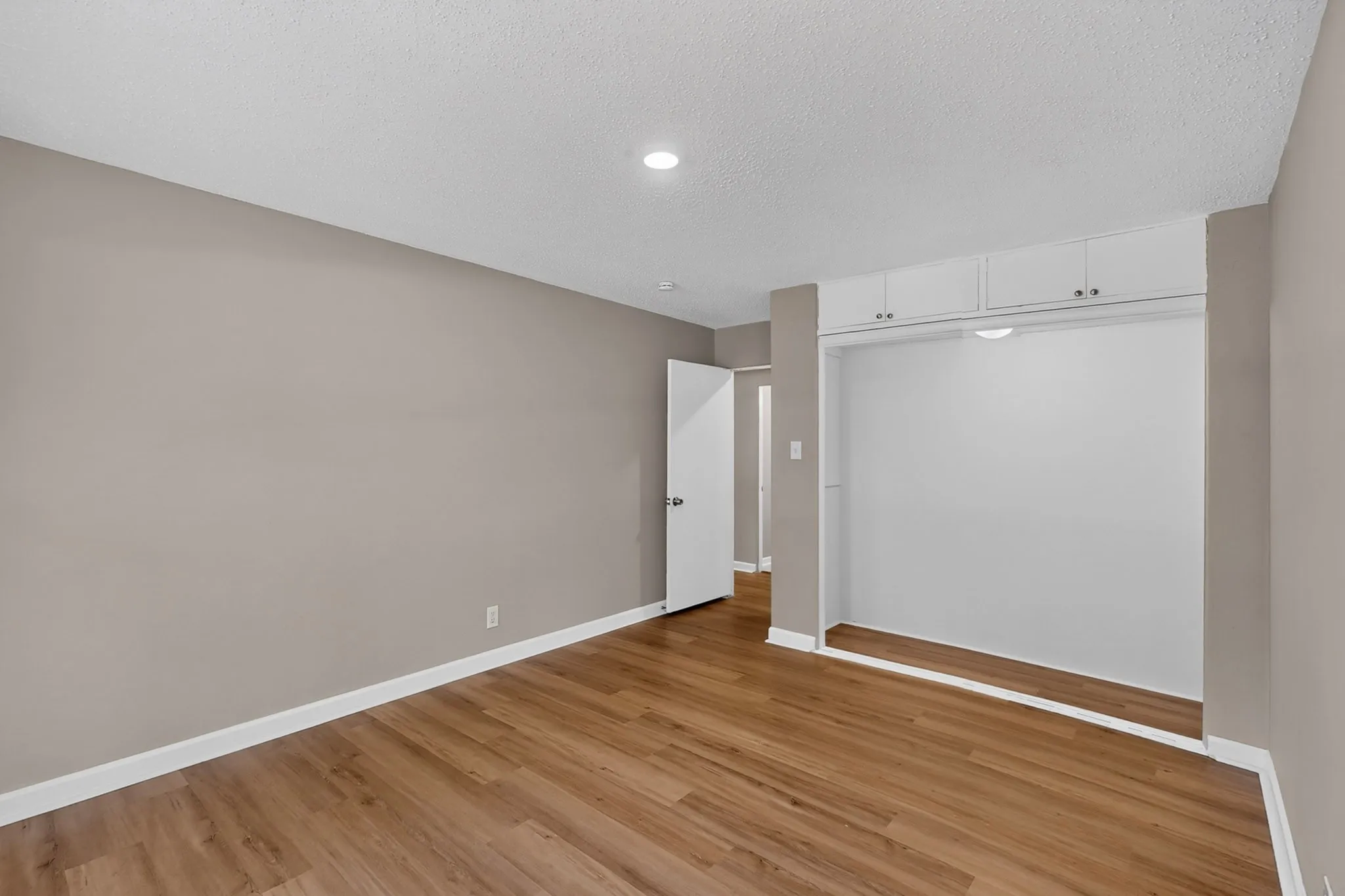 Wood-finish flooring, recessed lighting, built-in overhead cabinetry, and neutral wall tones