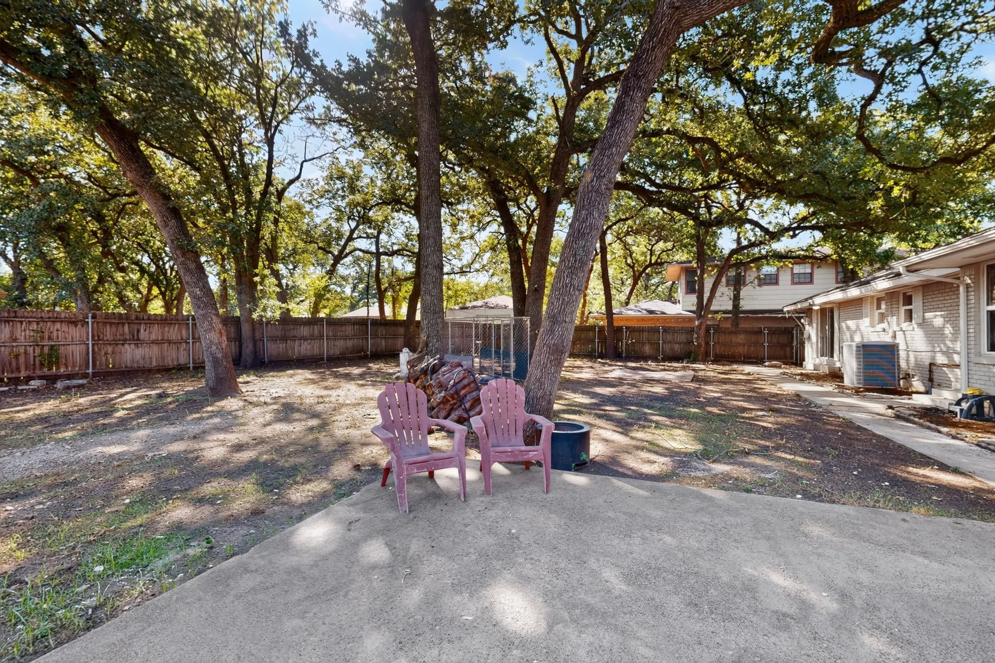 Expansive backyard featuring mature trees, a wood privacy fence, and a concrete patio