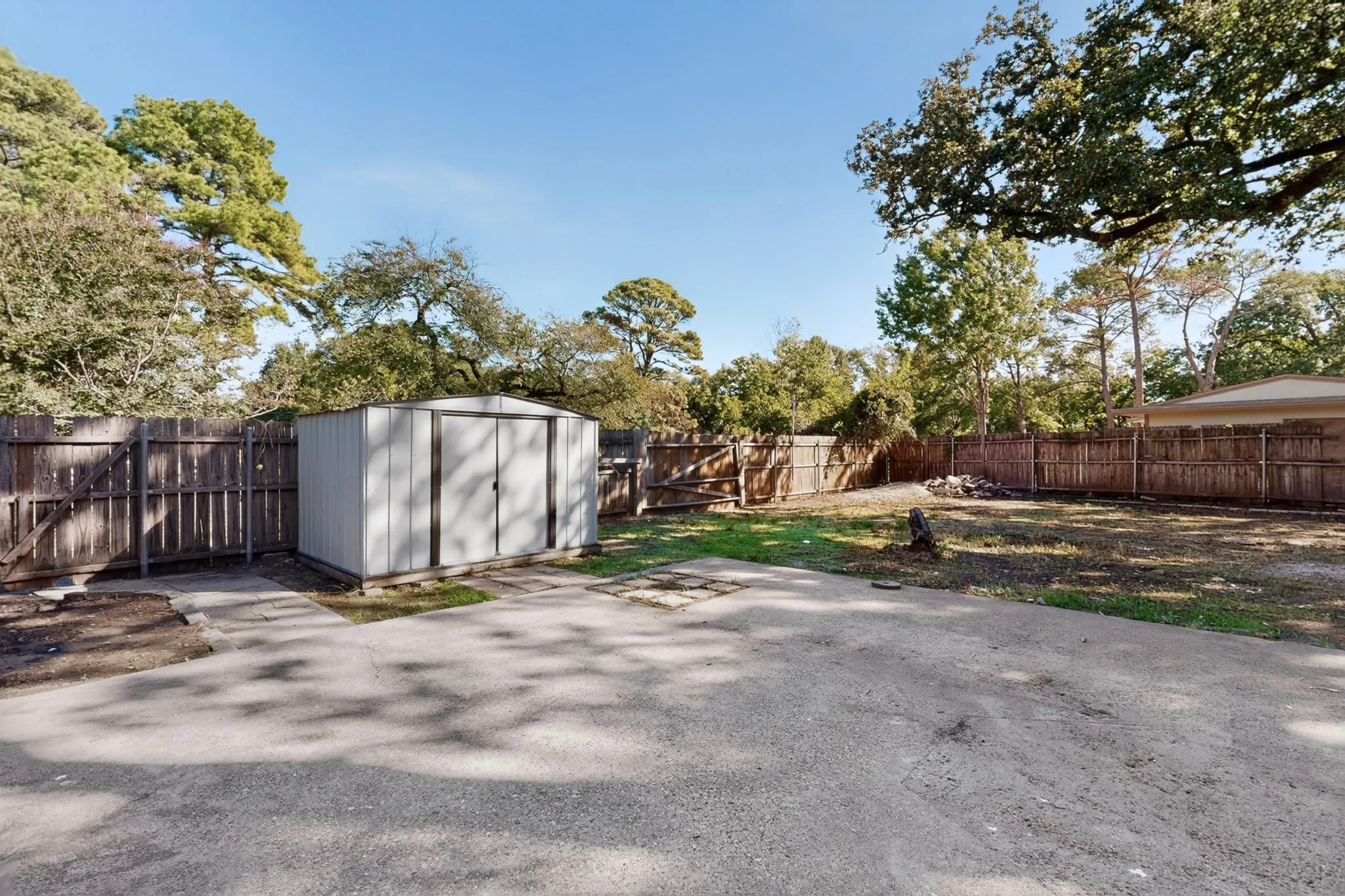 Spacious backyard featuring mature landscaping, lush green lawn, and a detached storage structure with modern finishes