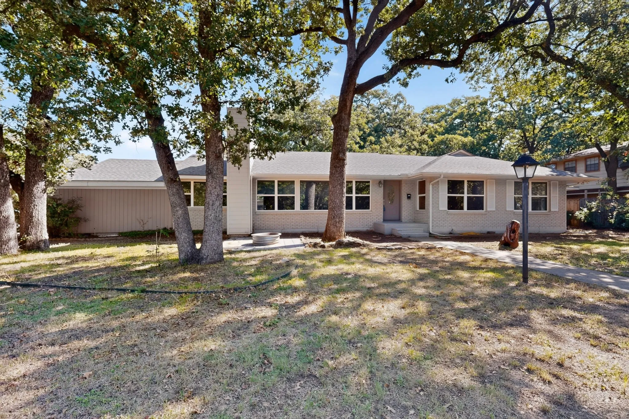 Ranch-style exterior with a light-colored brick facade, multiple windows, a prominent front door, and a concrete walkway