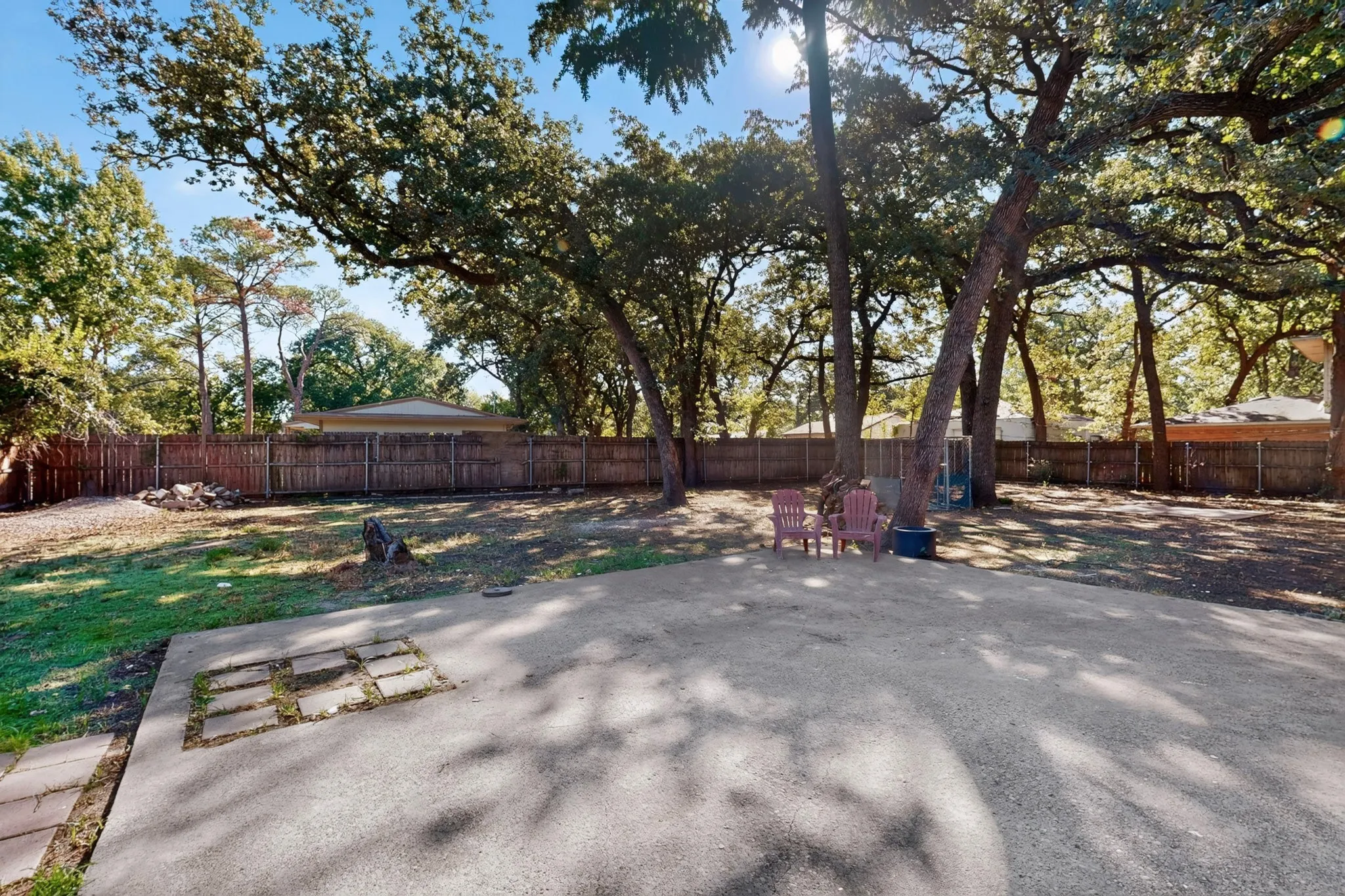 Expansive concrete patio with mature trees providing natural shade