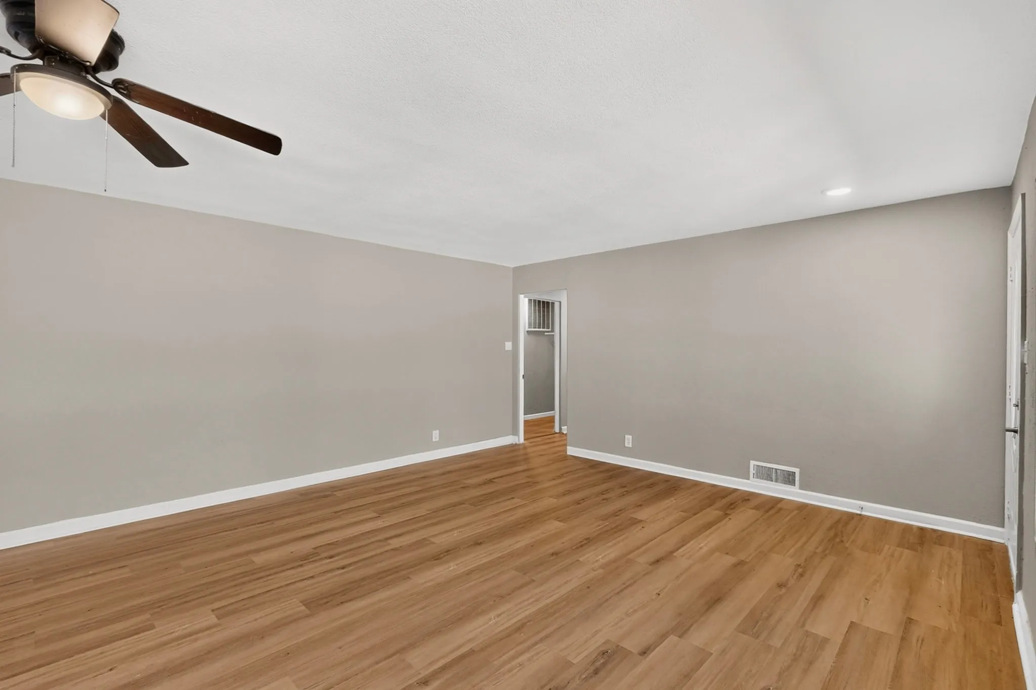 Wood-finish flooring, neutral gray wall tones, ceiling fan with integrated lighting, and recessed lighting