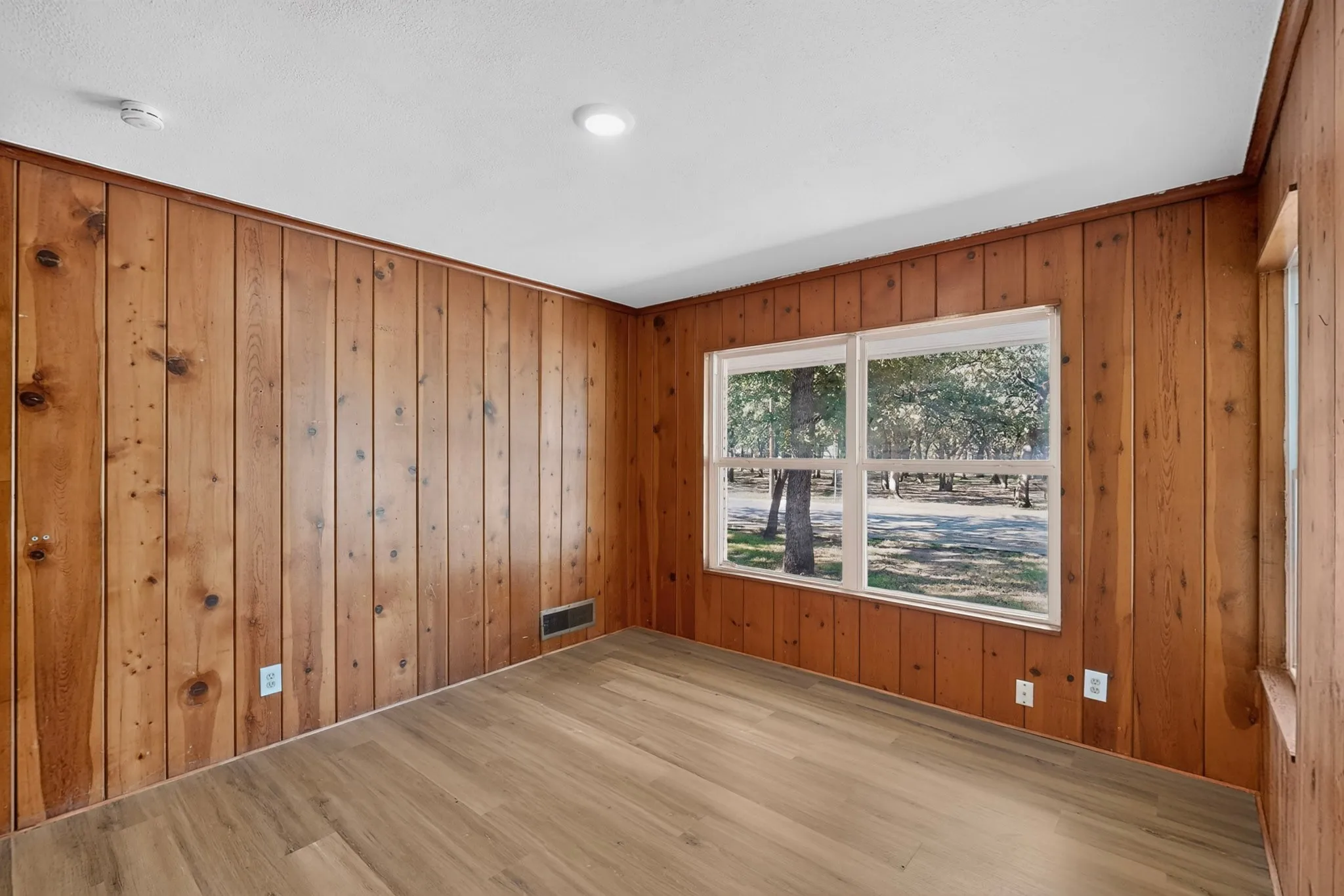 Wood-finish flooring with wood paneling walls and white trim