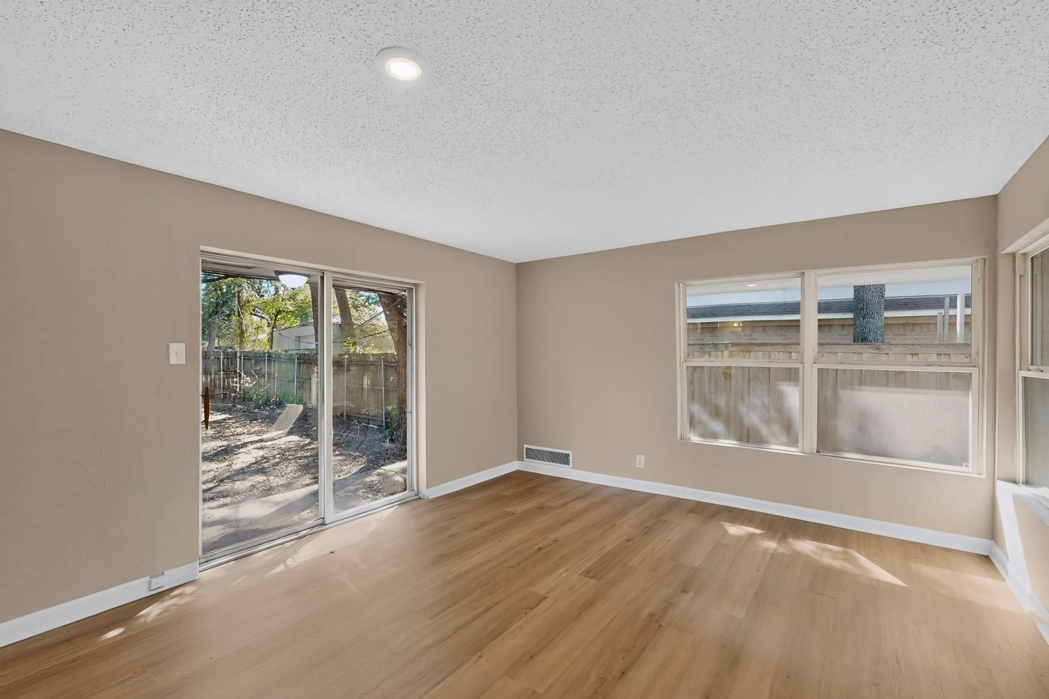 Recessed lighting, wood-finish flooring, sliding glass door, multiple windows, and neutral wall tones