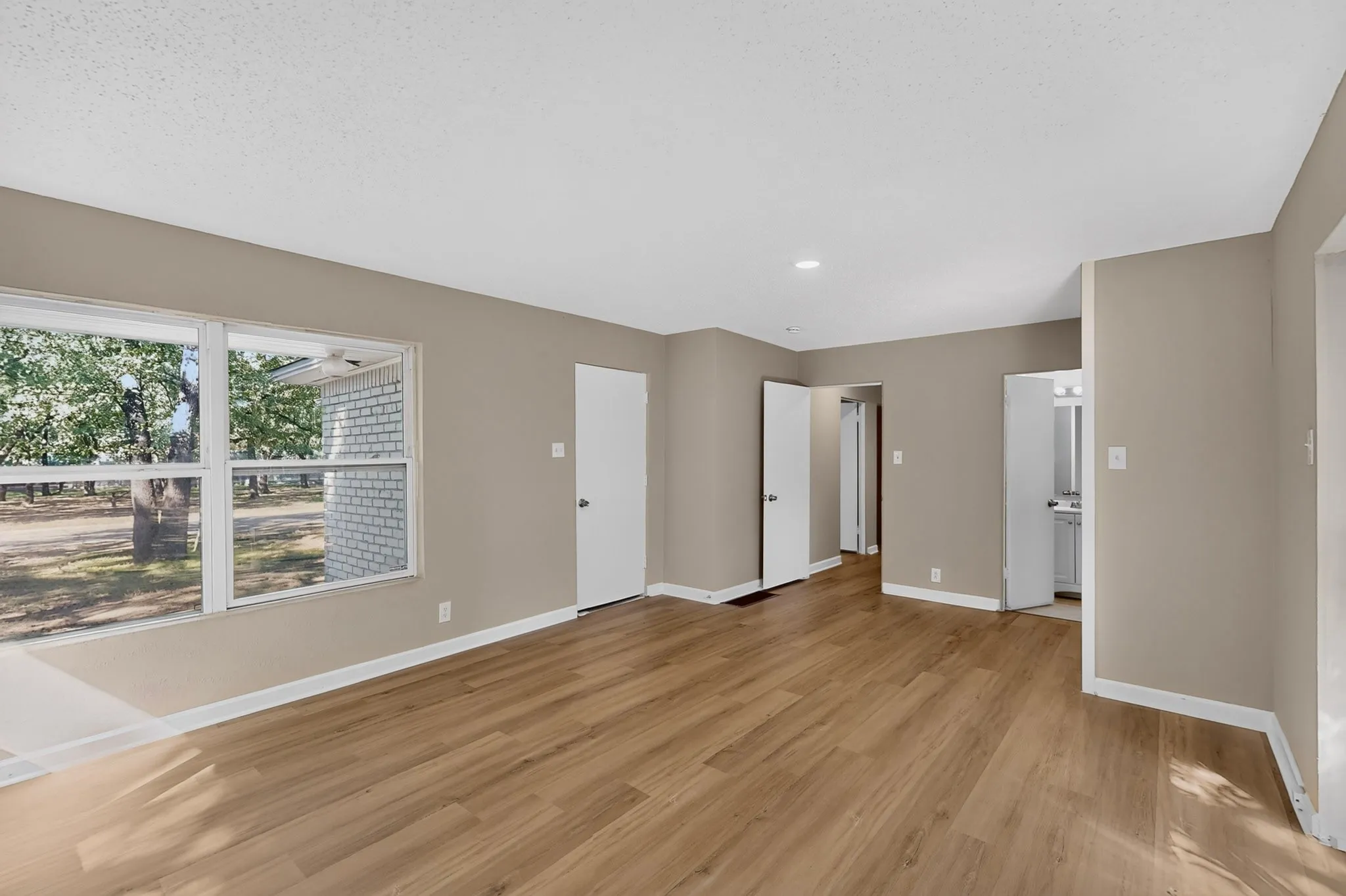 Wood-finish flooring, recessed lighting, neutral wall tones, and white trim throughout