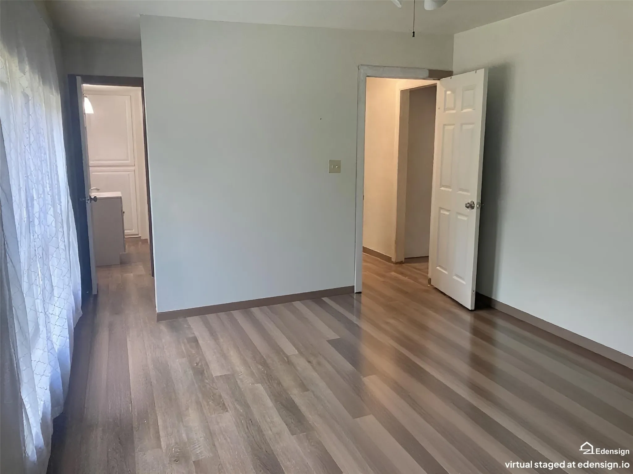 Wood-finish flooring throughout, white interior walls, and a ceiling fan