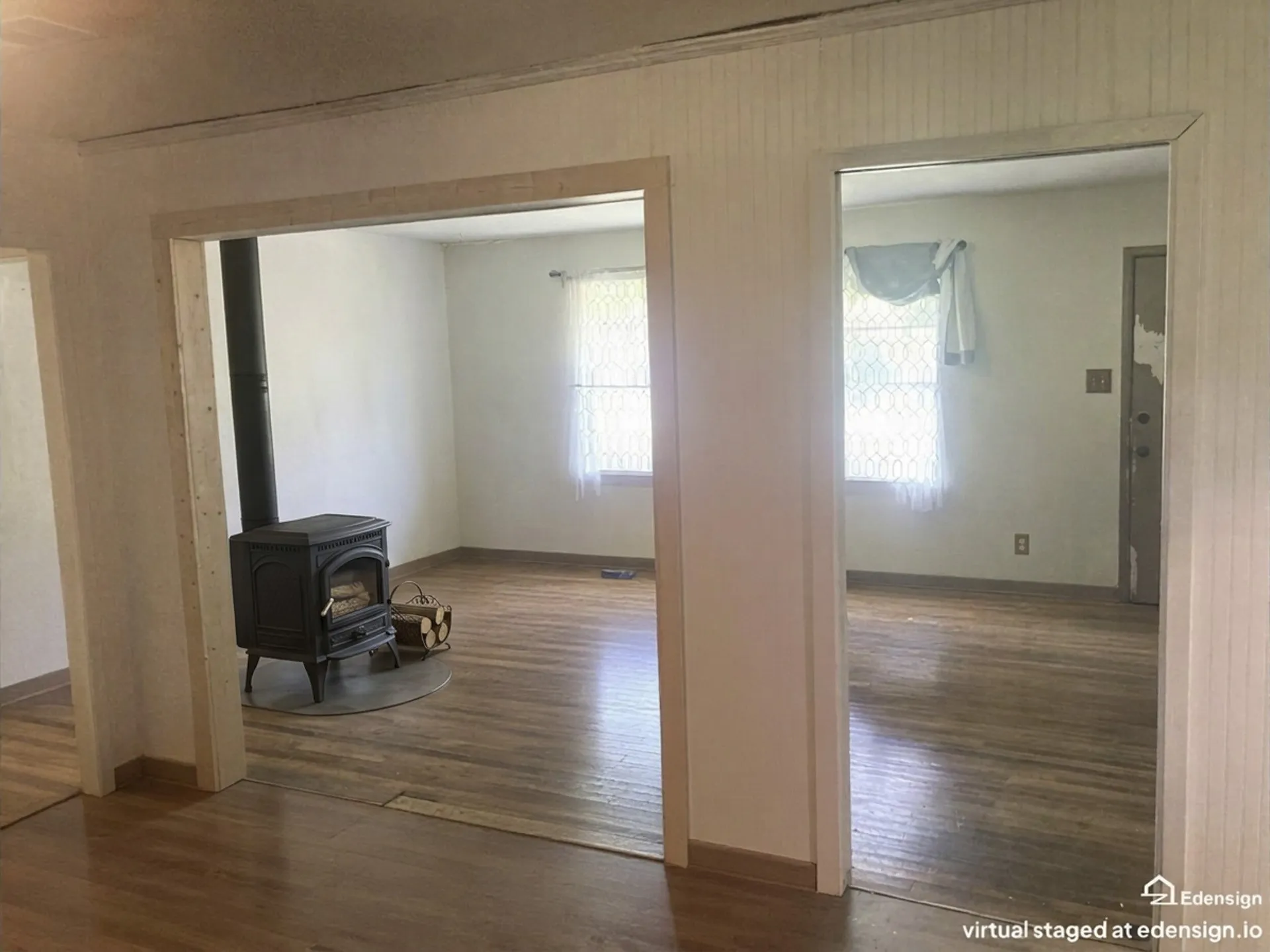 Wood-finish flooring throughout, featuring a cast-iron stove with an exposed flue, and multiple cased openings