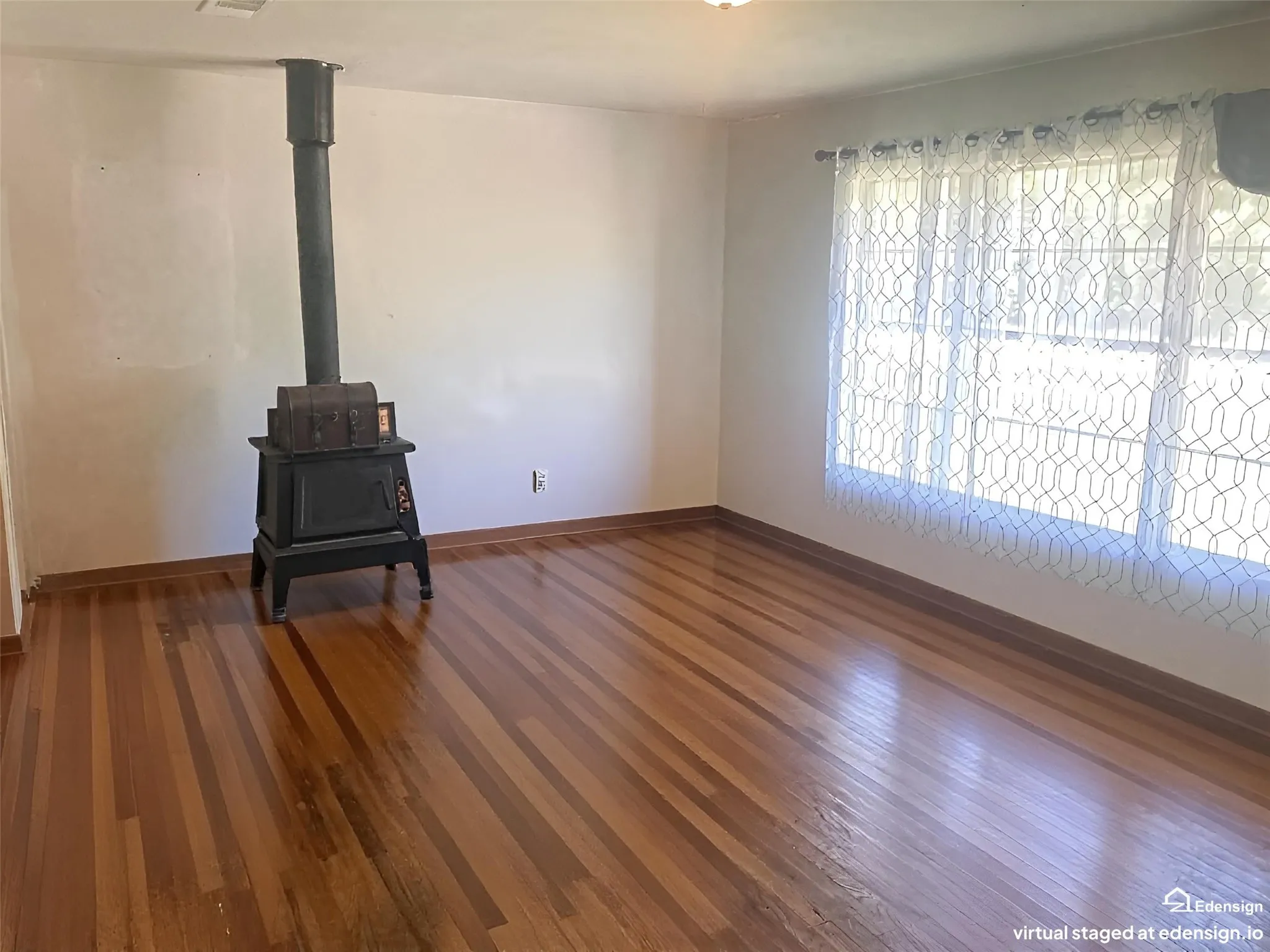 Polished wood-finish flooring, cast iron stove, and large window