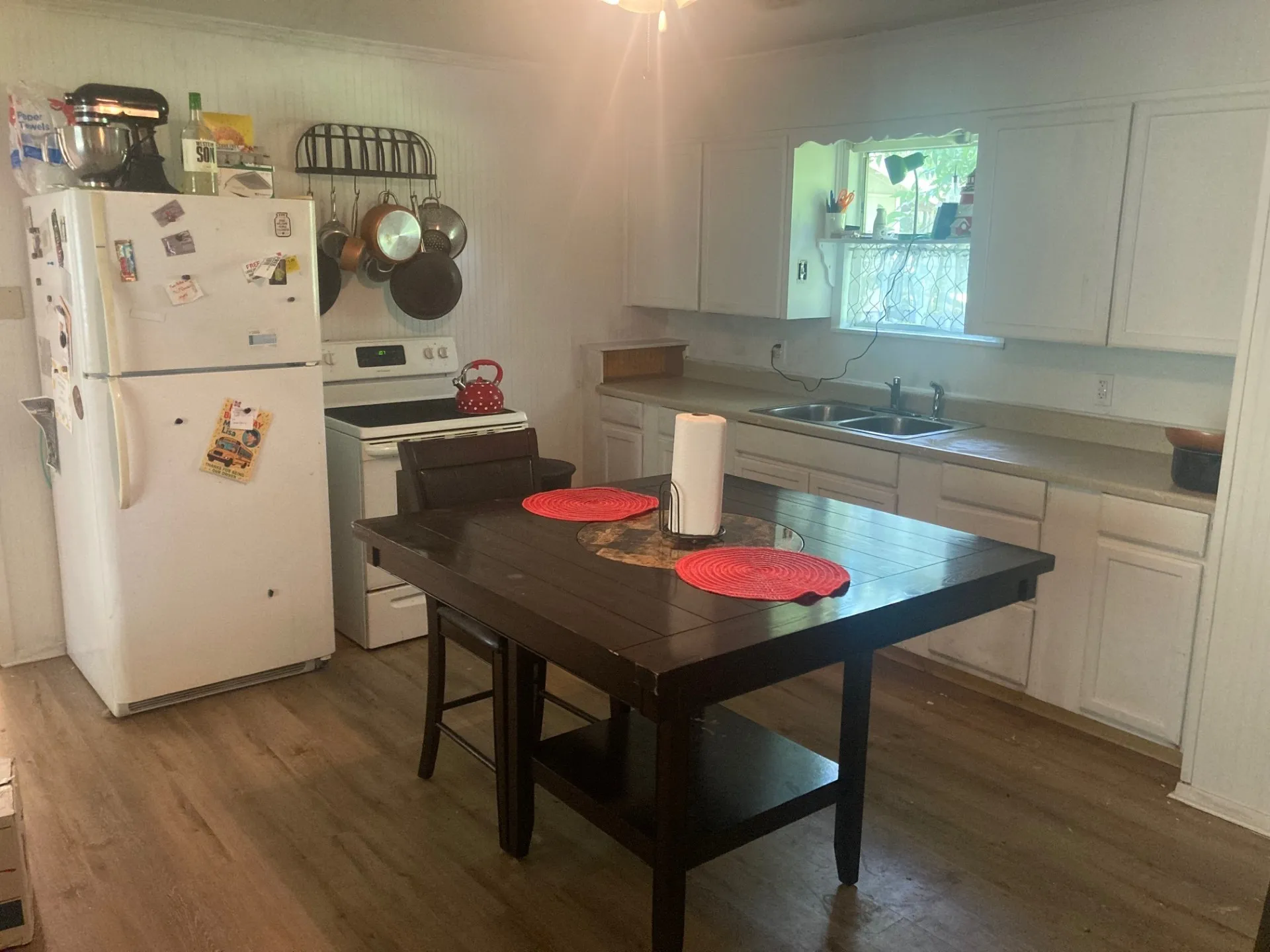 Kitchen featuring wood-finish flooring, white cabinetry, a double basin sink, and a window