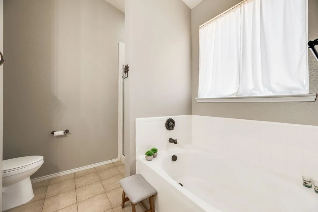 Integrated soaking tub with dark bronze fixtures, white tile surround, and a clear glass shower enclosure