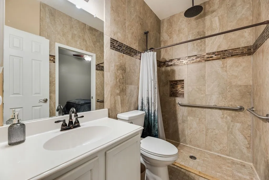 Tiled shower with mosaic accent, built-in niche, and dark bronze rainfall showerhead