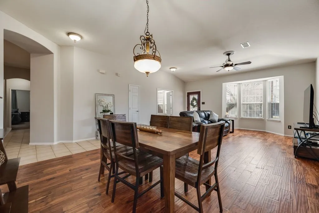 Open-concept living area with wood-finish flooring, a decorative chandelier, and a ceiling fan
