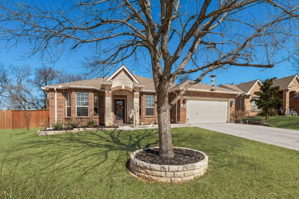 Brick and stone facade, arched entryway, bay window, two-car garage, and a manicured lawn