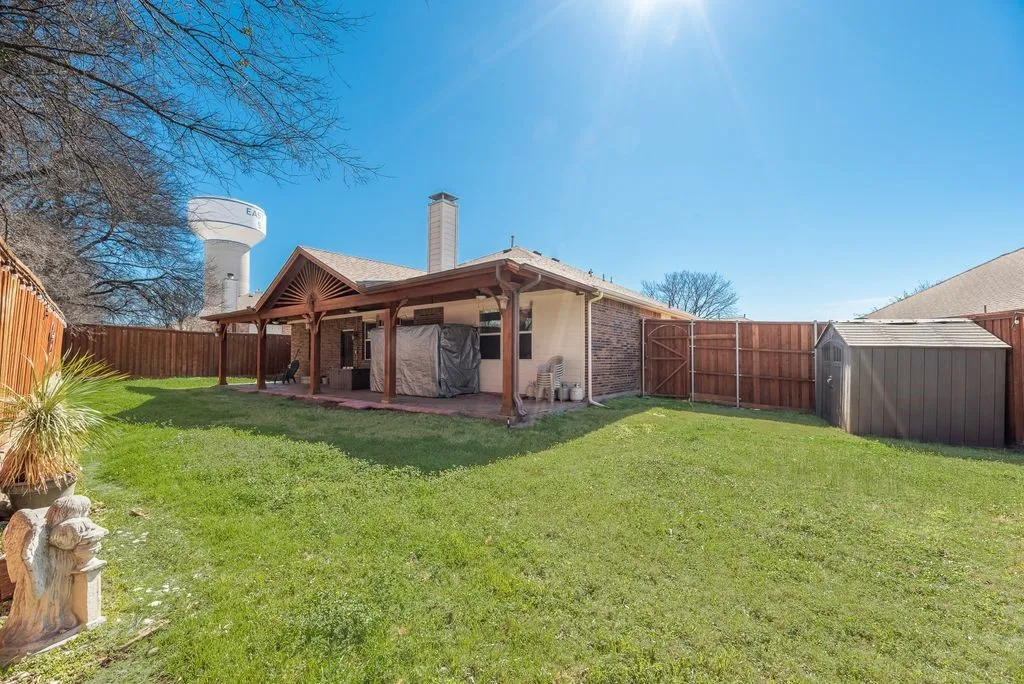 Expansive backyard with a covered patio, wood pergola, and a storage shed