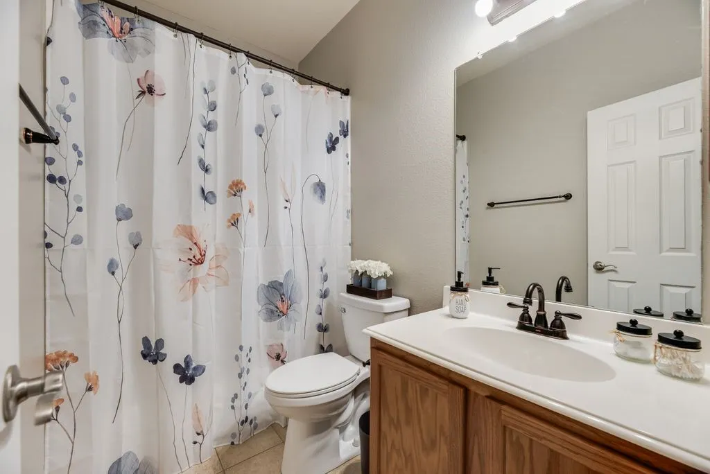 White vanity with a single basin sink, bronze-finish faucet, and wood-finish cabinetry
