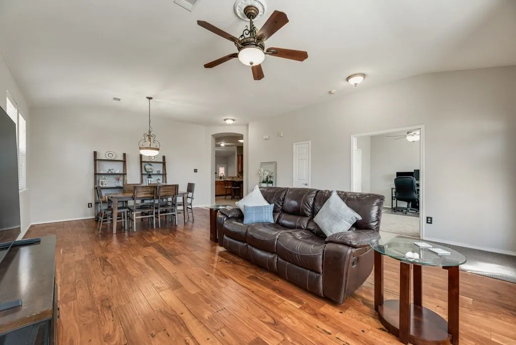 Open-concept living space featuring wood-finish flooring, a decorative ceiling fan, and recessed lighting