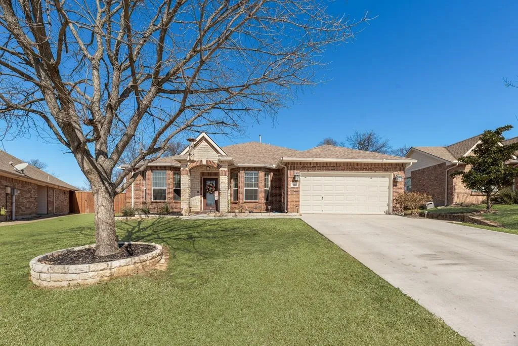 Brick exterior with stone accents, covered entry, attached garage, and concrete driveway