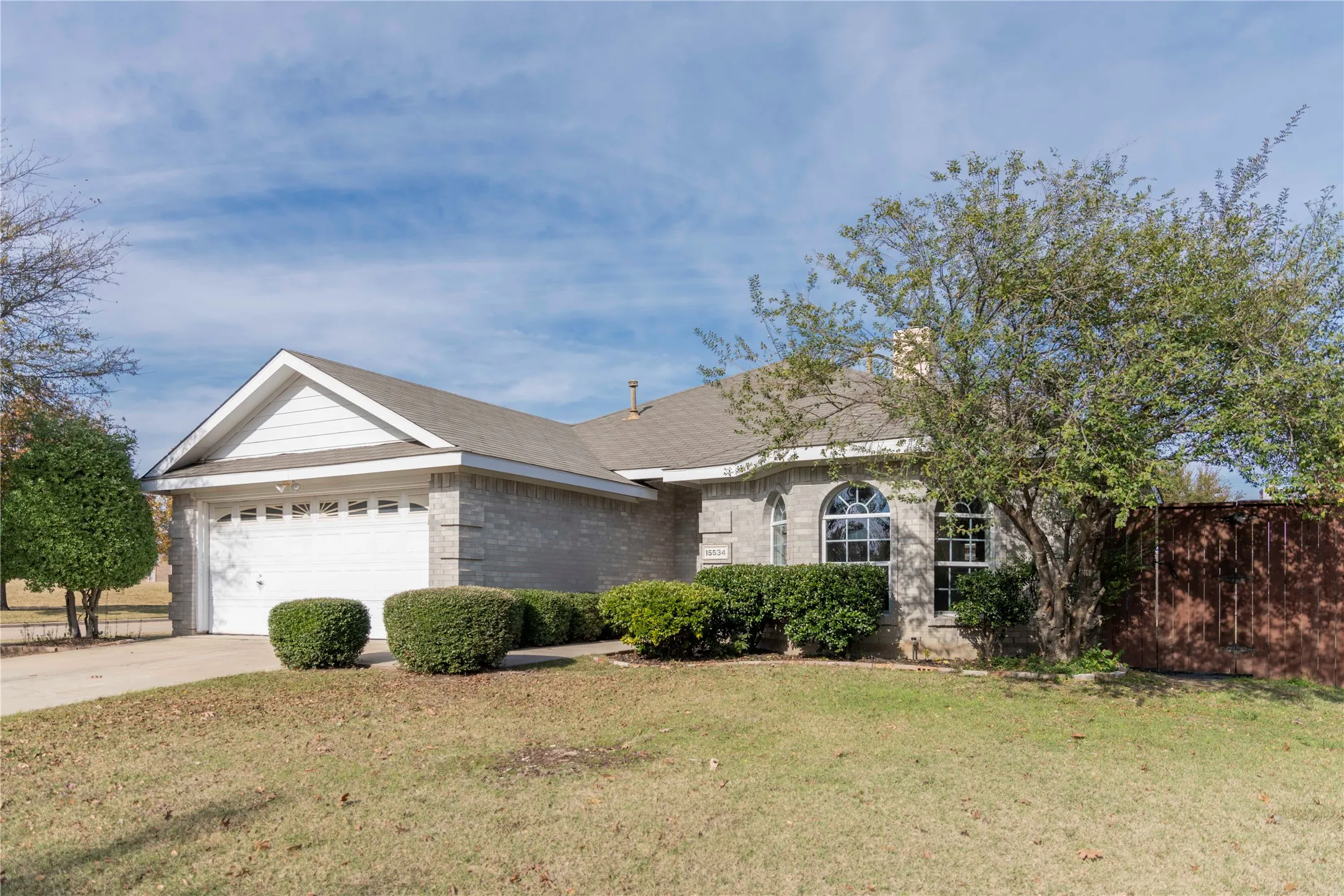 Single-story residence featuring light-colored brick exterior, attached garage, and arched window