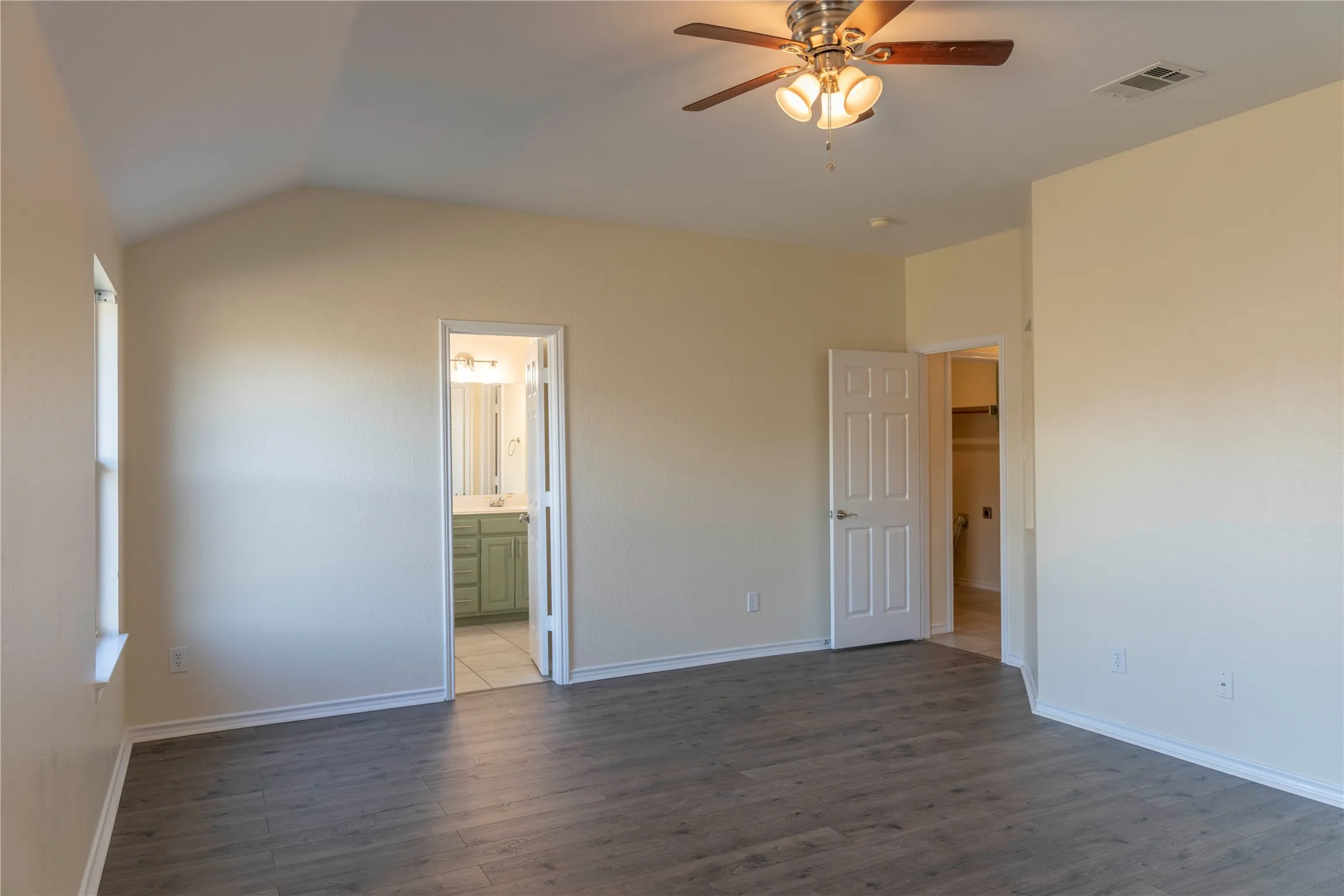 Vaulted ceiling with a ceiling fan, wood-finish flooring, and white trim