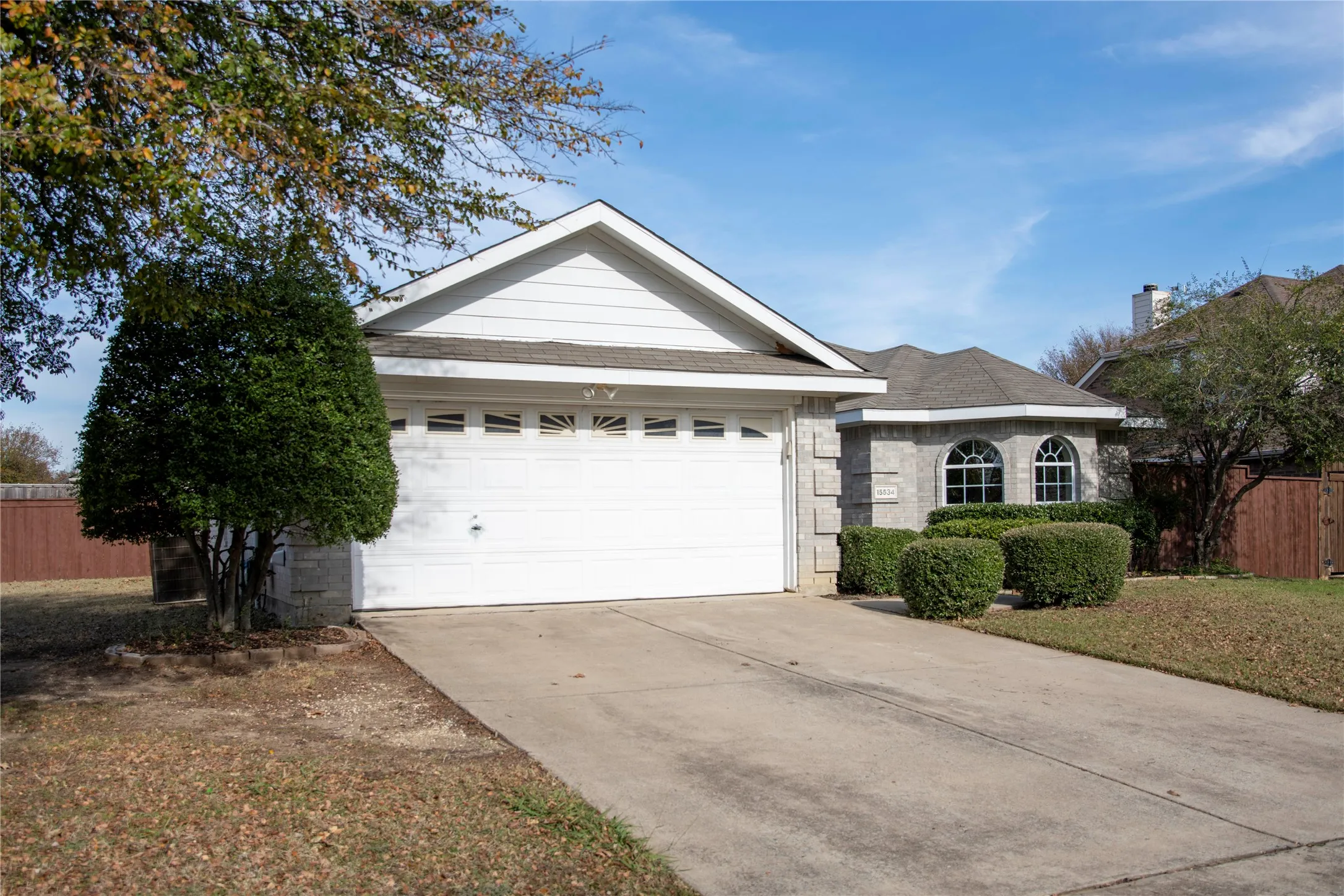 Stone veneer exterior with arched windows, shingled roof, and an attached two-car garage