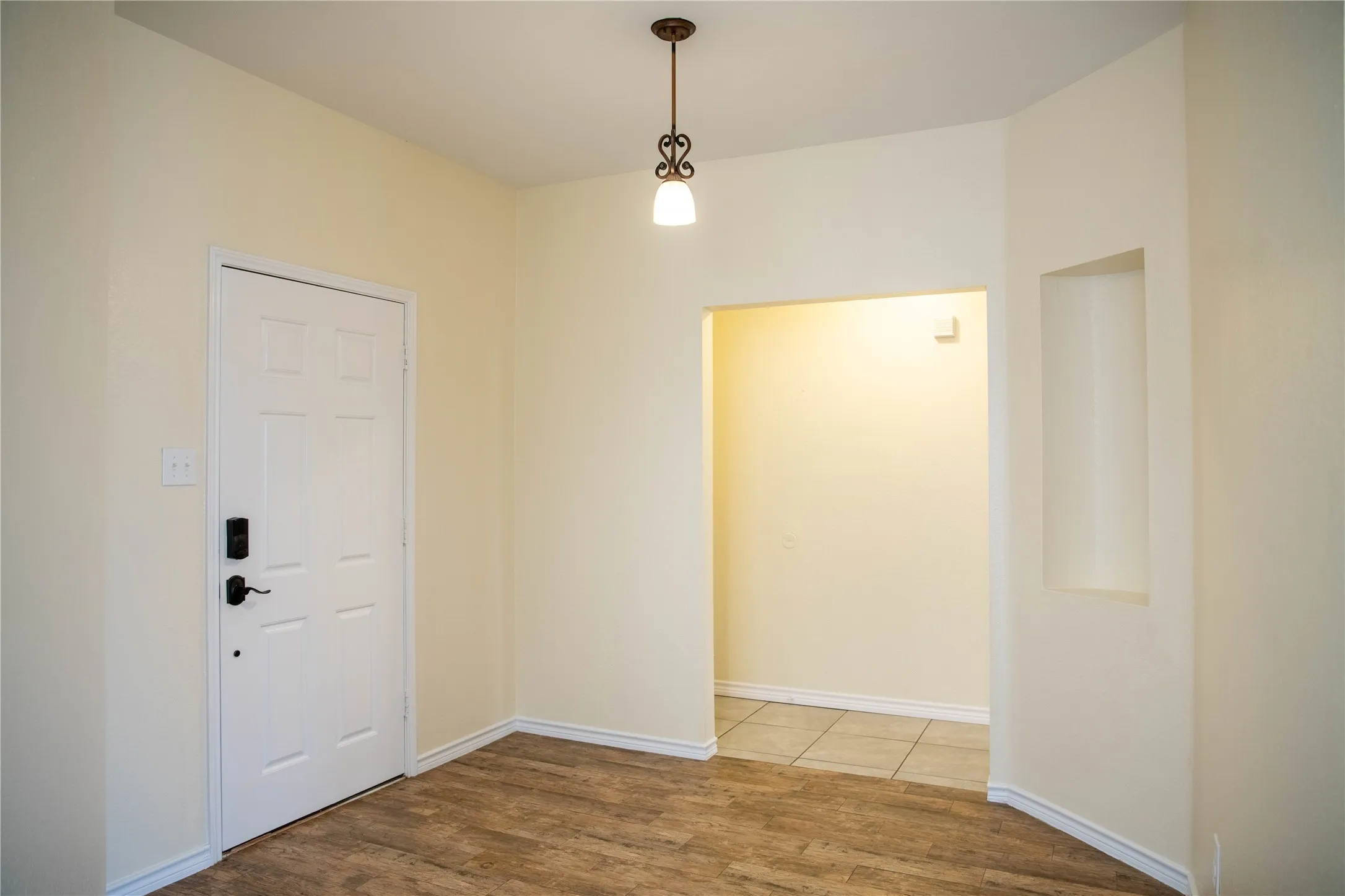 Wood-finish flooring with light-toned walls, a decorative ceiling fixture, and a built-in wall niche