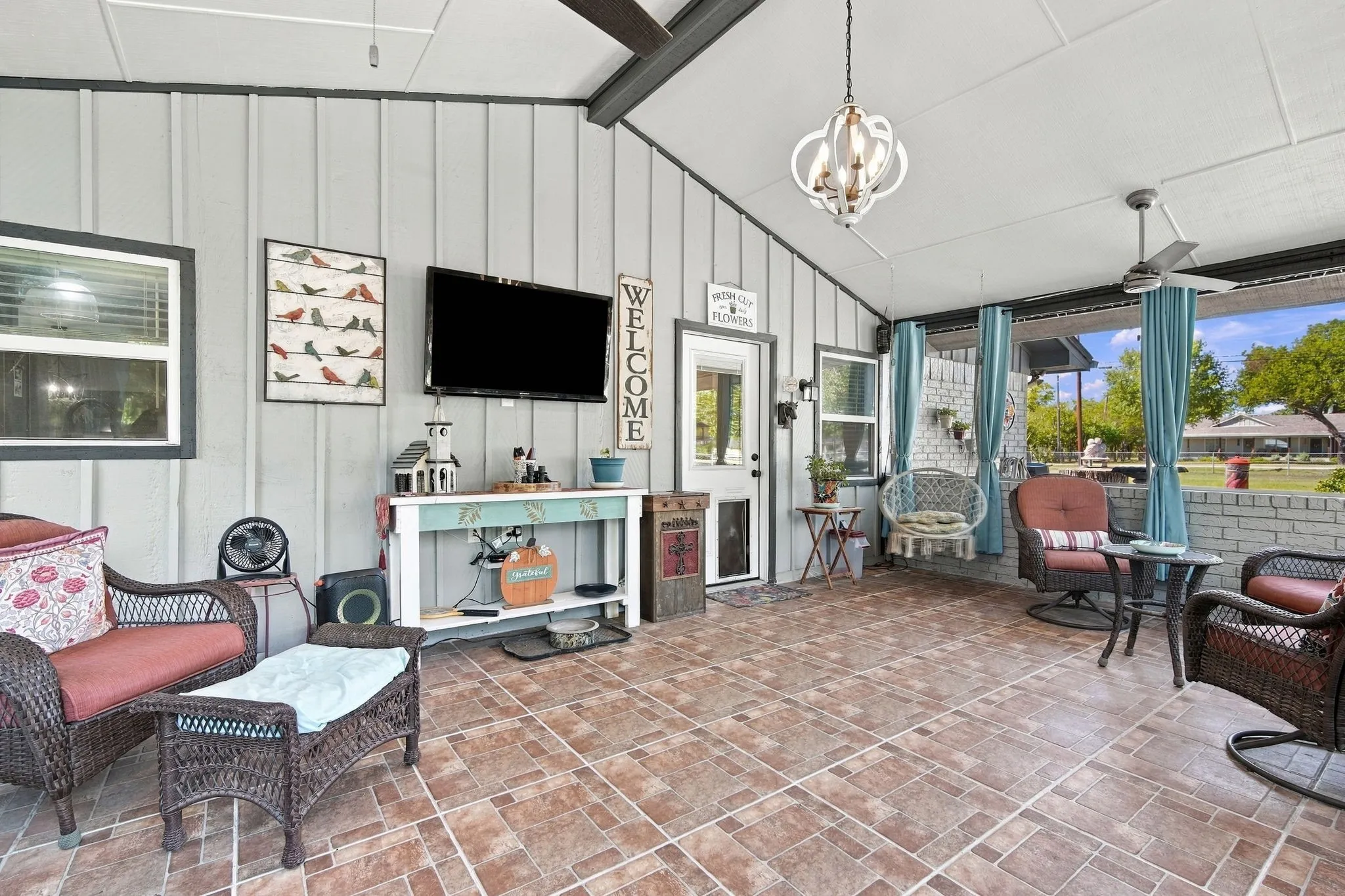 Covered outdoor screened in patio featuring tile flooring, a sloped ceiling, and multiple ceiling fans