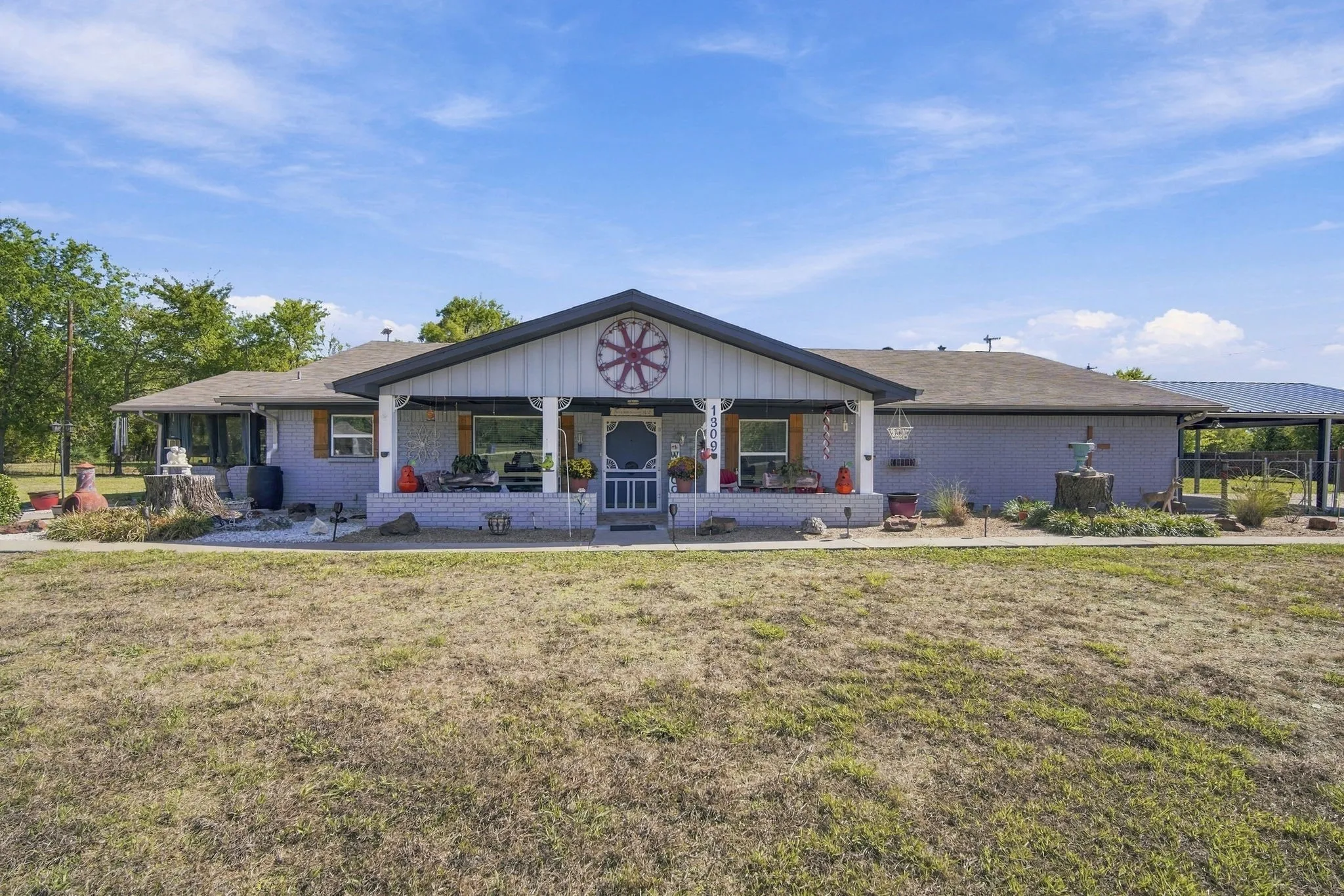 Expansive front porch with white columns, light gray exterior siding, and a covered carport structure