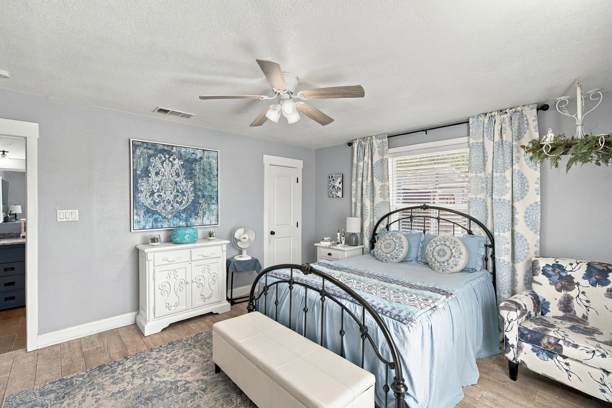 Wood-finish flooring, ceiling fan with light fixture, window with blinds, and white trim throughout