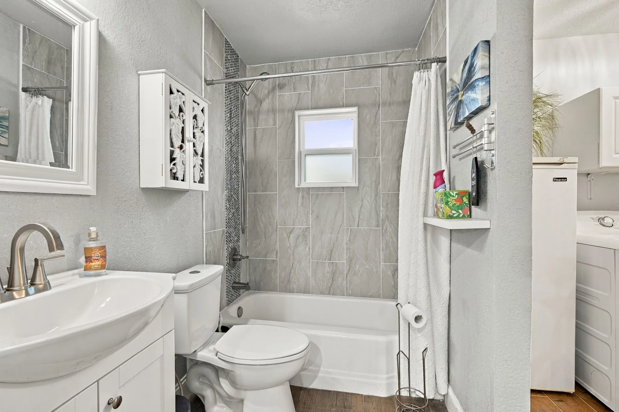 Integrated laundry area, full bathroom with a built-in tub, ceramic tile surround, and a vanity with a vessel sink