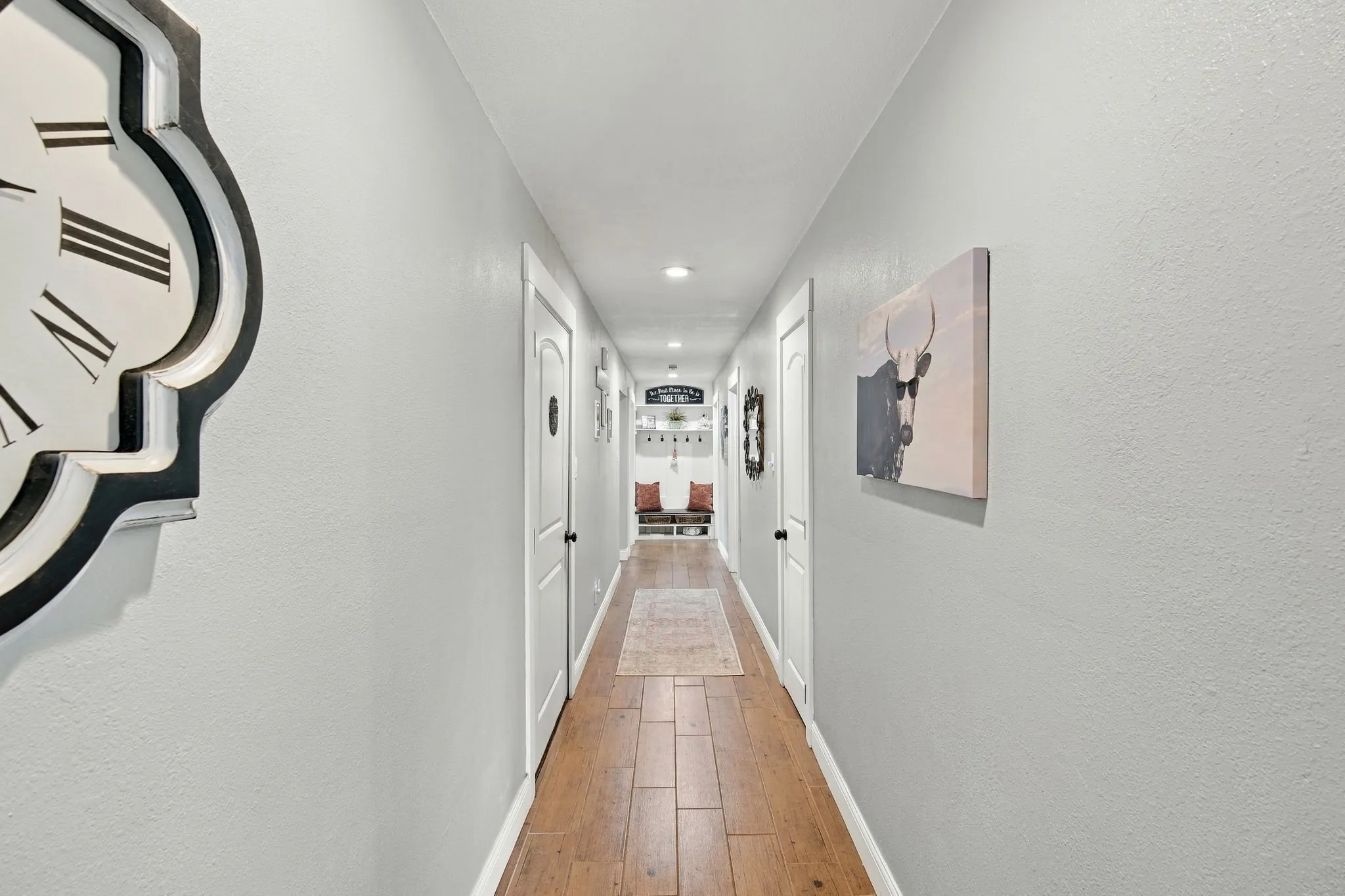 Hallway with wood-finish flooring, recessed lighting, white doors with black hardware, and light-toned wall finishes built in storage