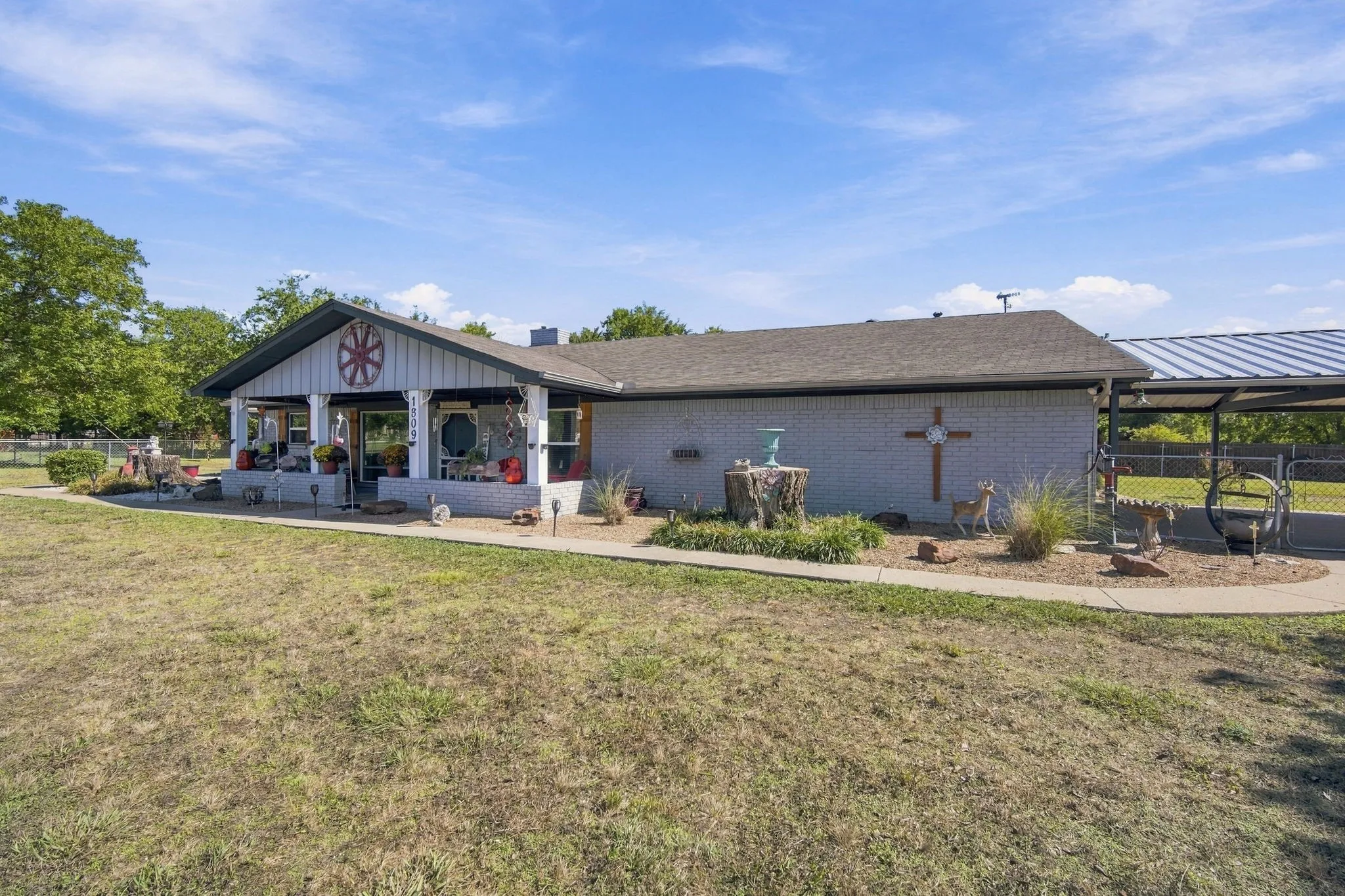 Covered front porch with white columns, brick exterior, and attached carport