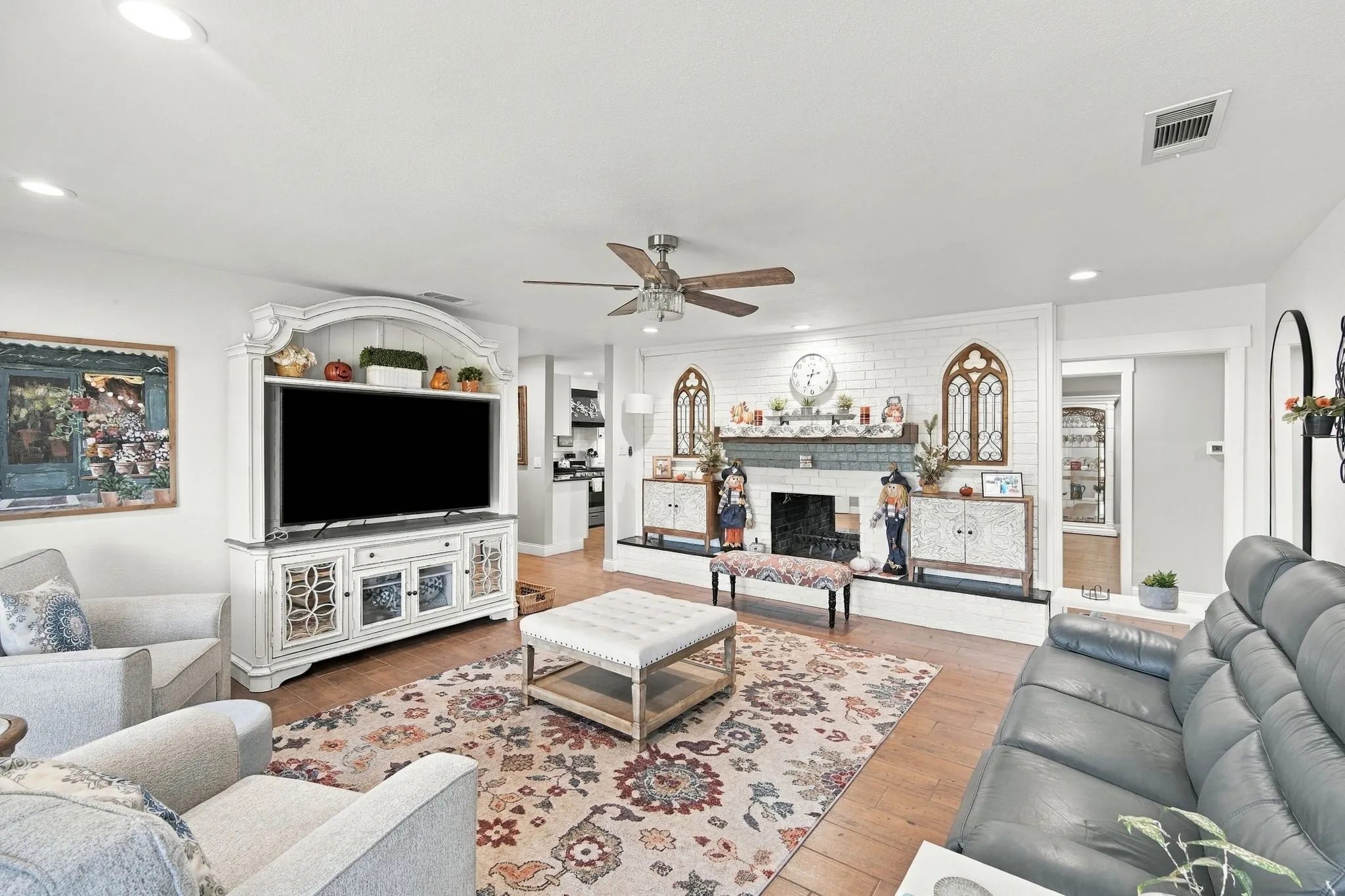 Recessed lighting illuminates wood-finish flooring and featuring double sided fireplace