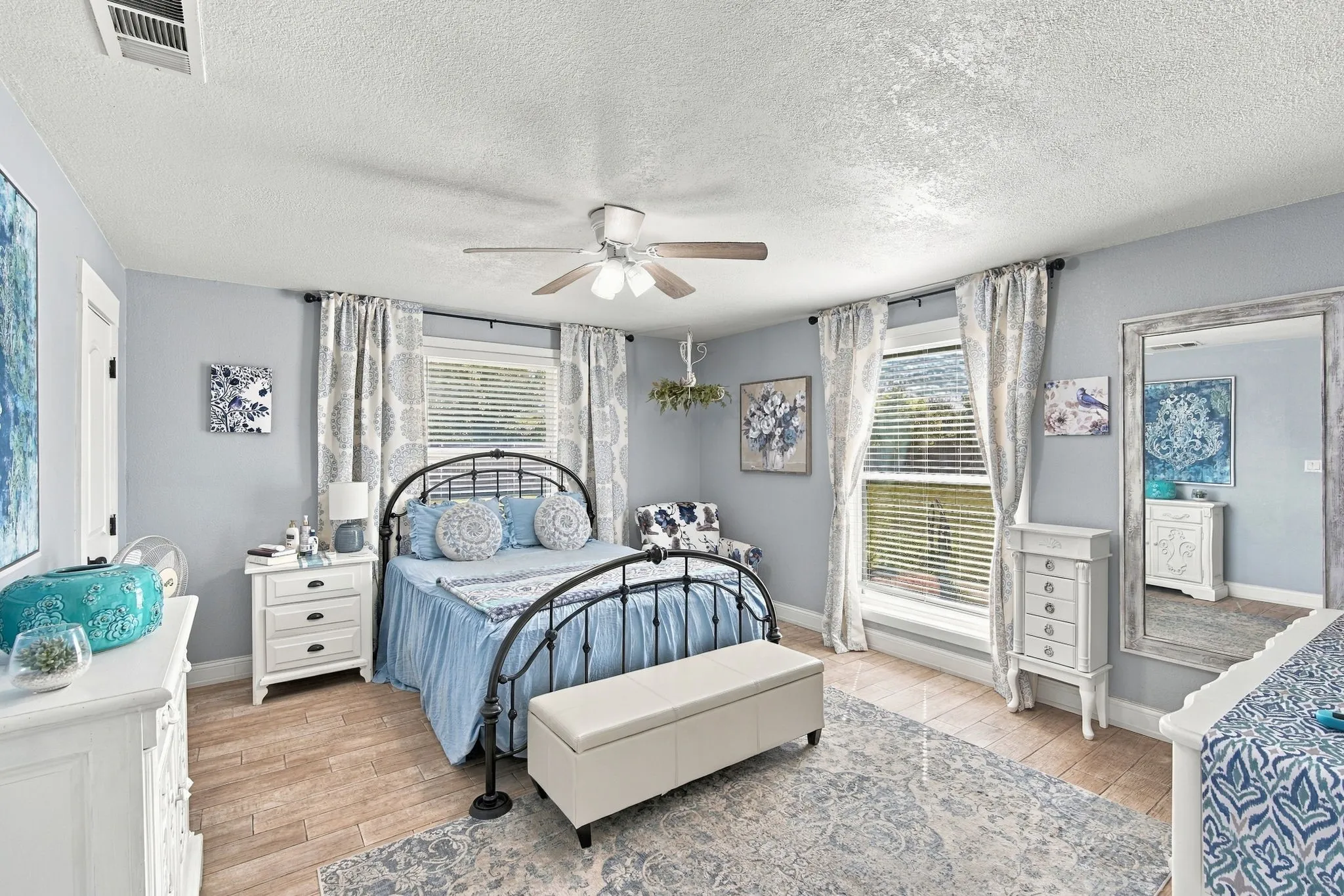 Recessed lighting, ceiling fan, wood-finish flooring, multiple windows, and light blue wall tones