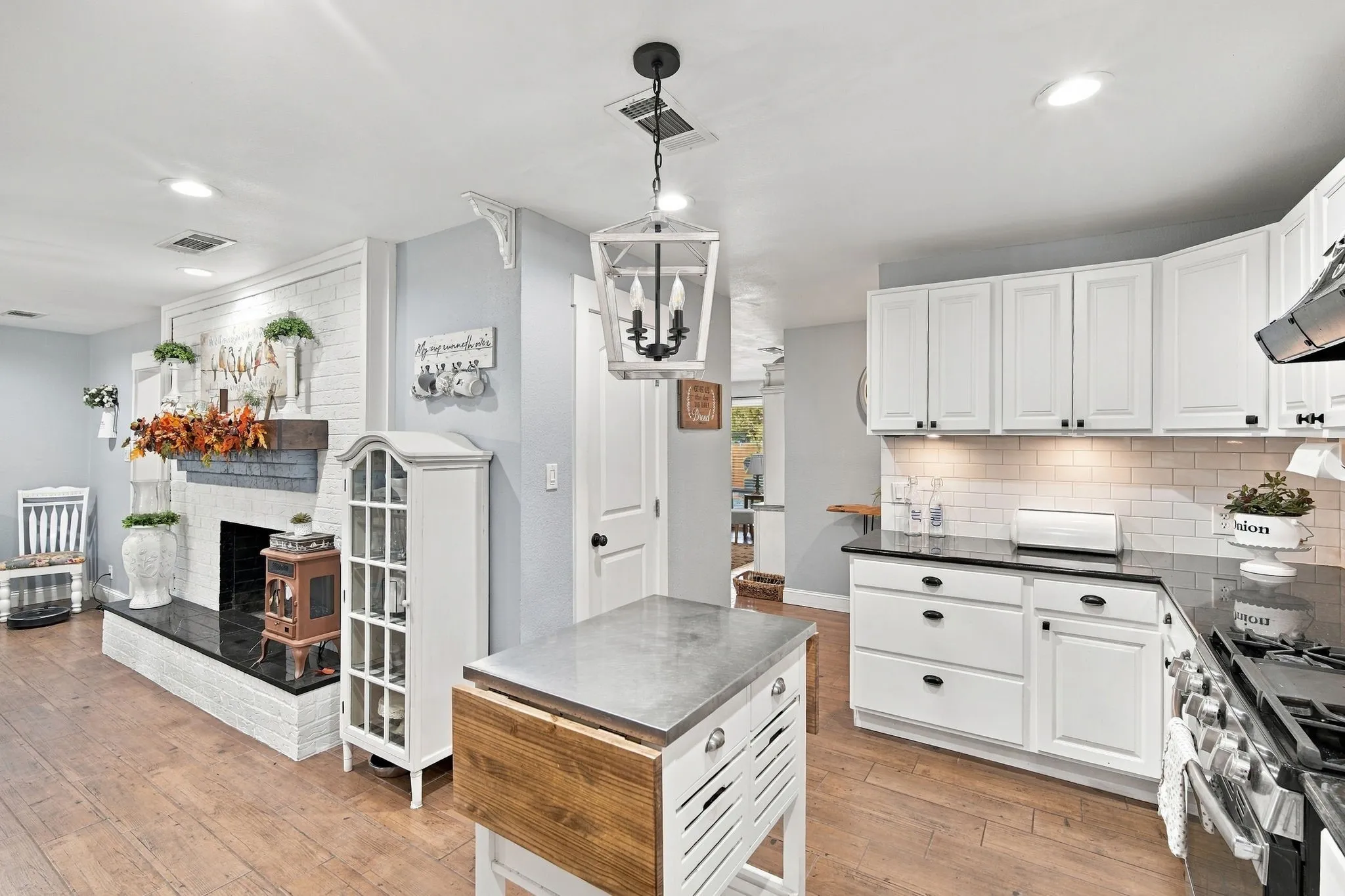 Kitchen featuring white cabinetry with black hardware, black countertops, and a white subway tile backsplash