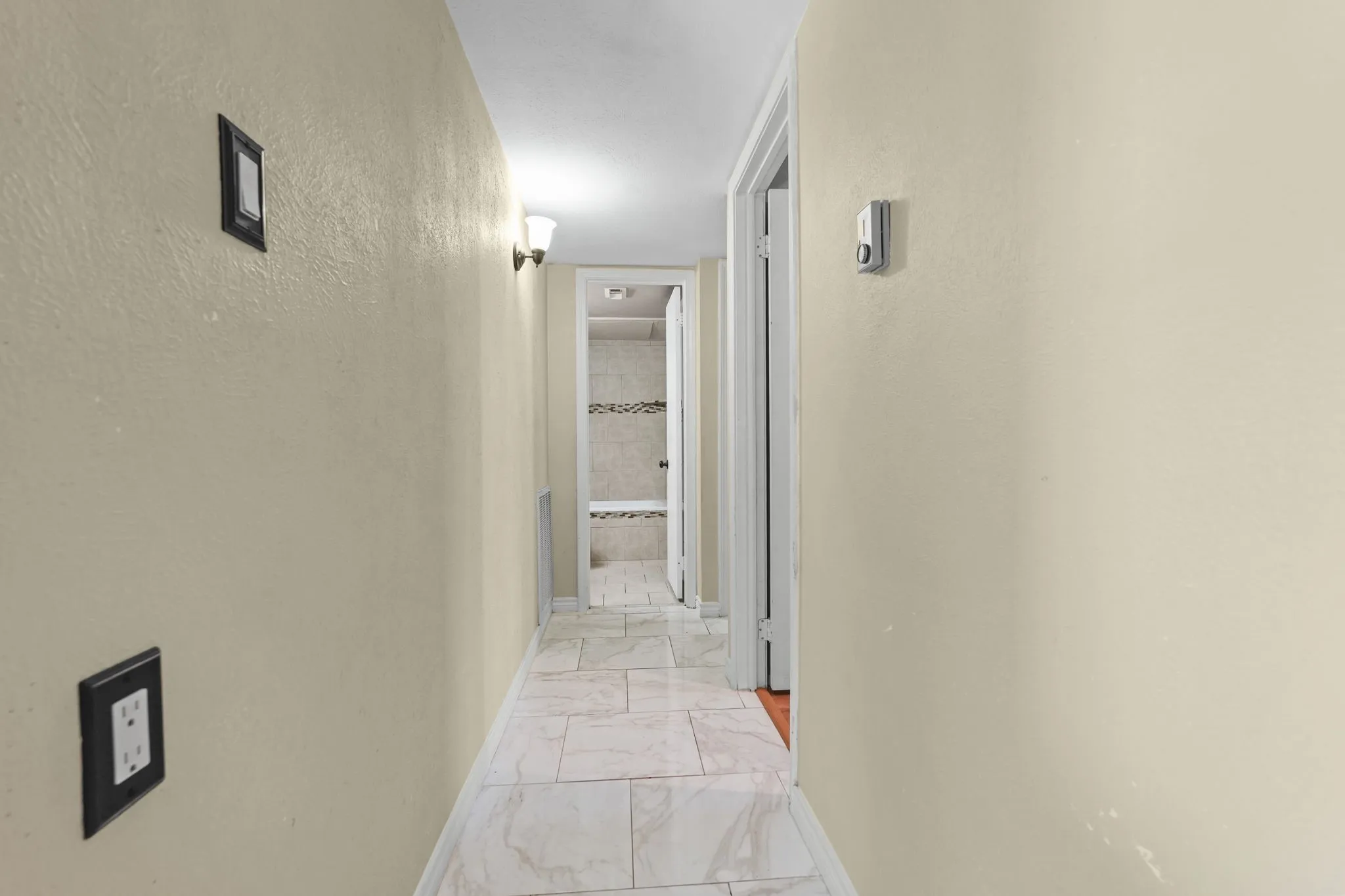 Hallway featuring tiled flooring, recessed ceiling lighting, and wall-mounted sconces