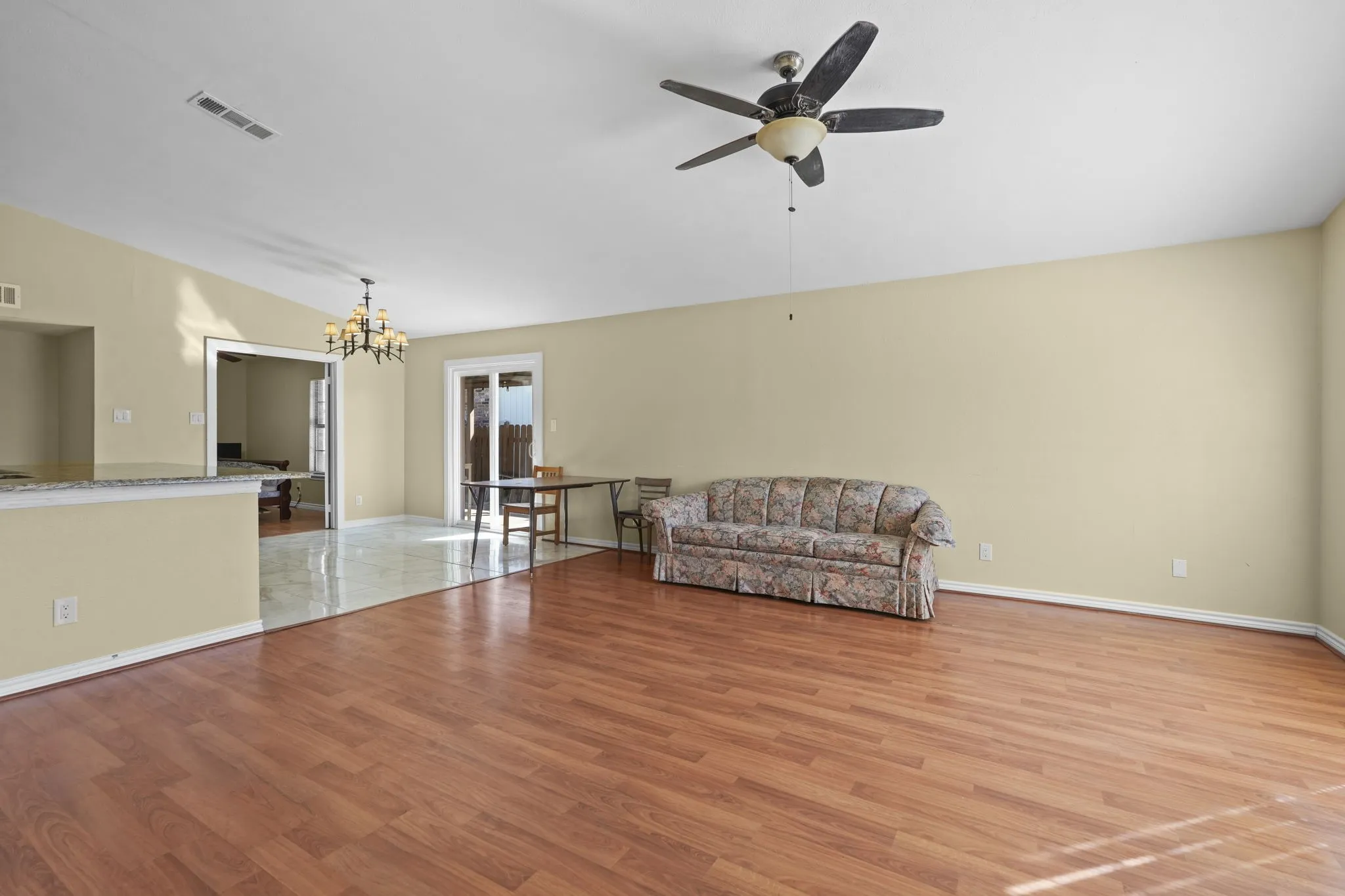 Spacious living area featuring wood-finish flooring, a ceiling fan, and a light-toned wall finish