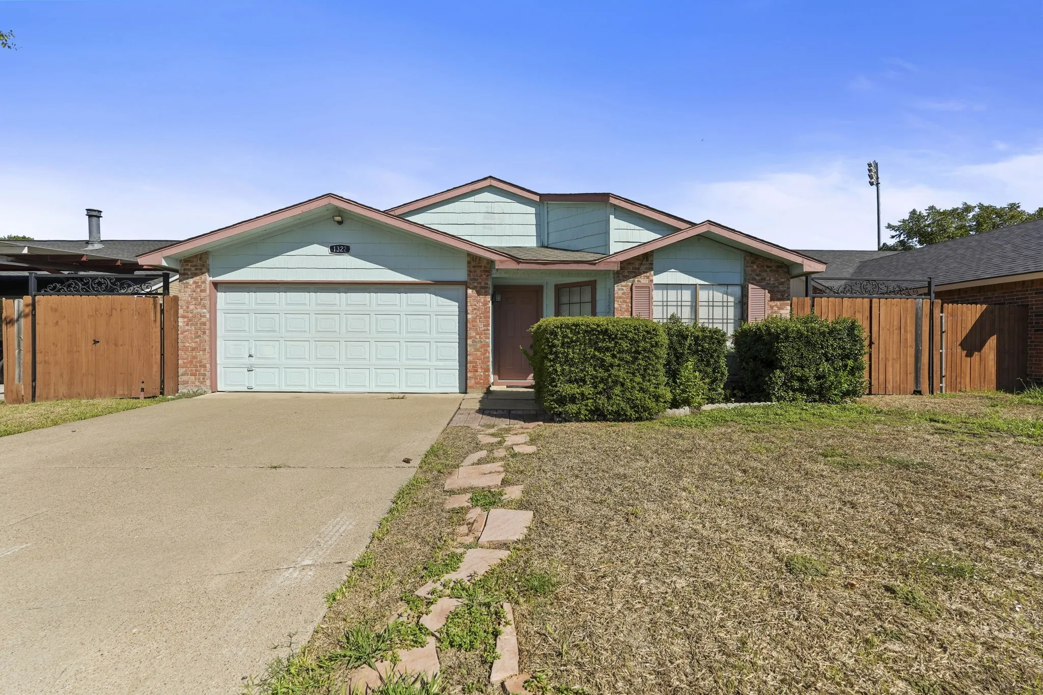 Brick and siding exterior with a garage, concrete driveway, and stone pathway