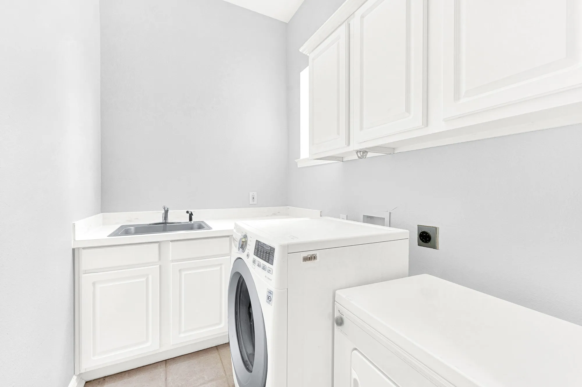 Utility room features utility sink, cabinets, and counter space for folding