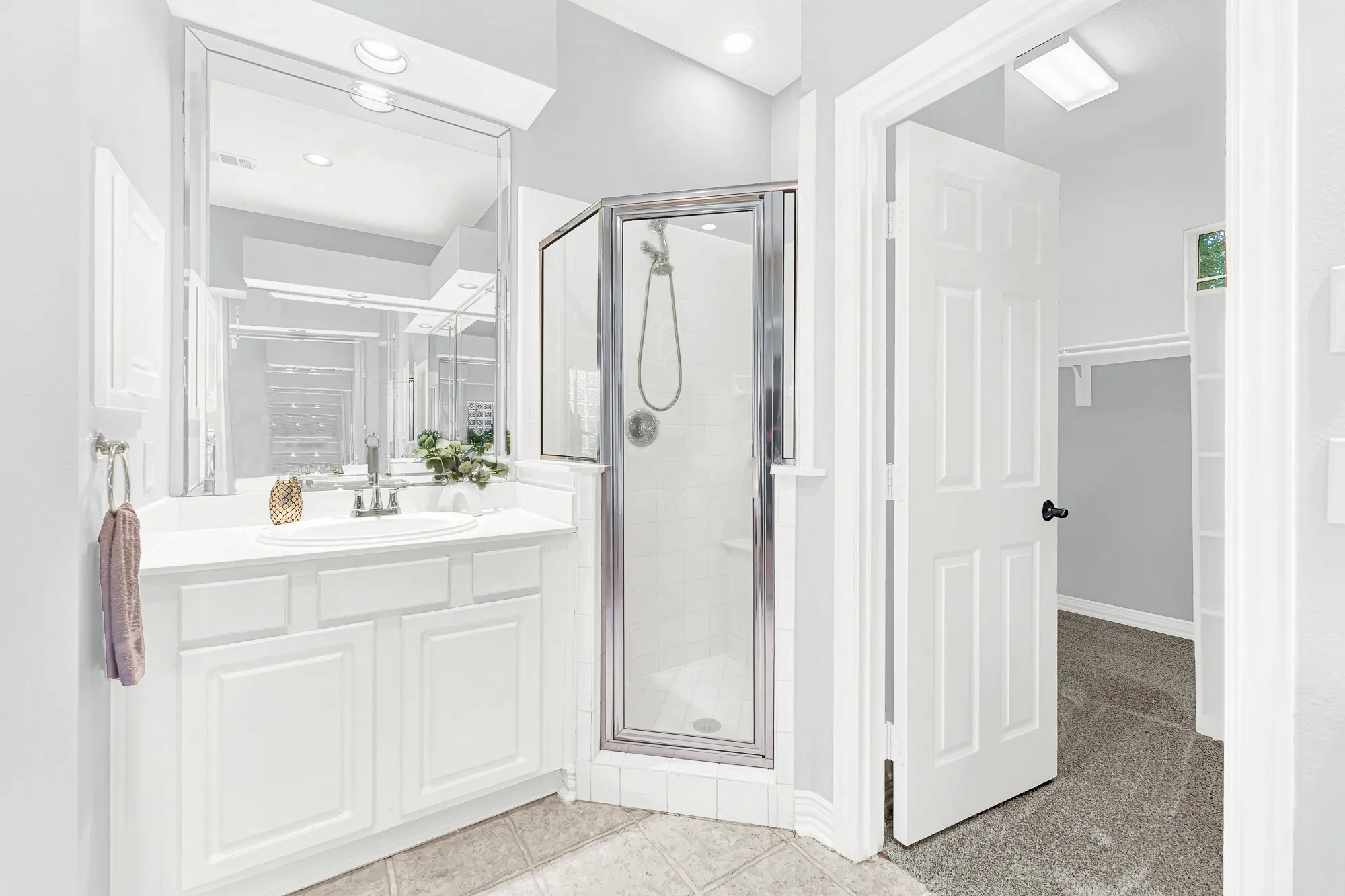 Primary bathroom offers separate vanities, a walk-in shower, and a large walk-in closet