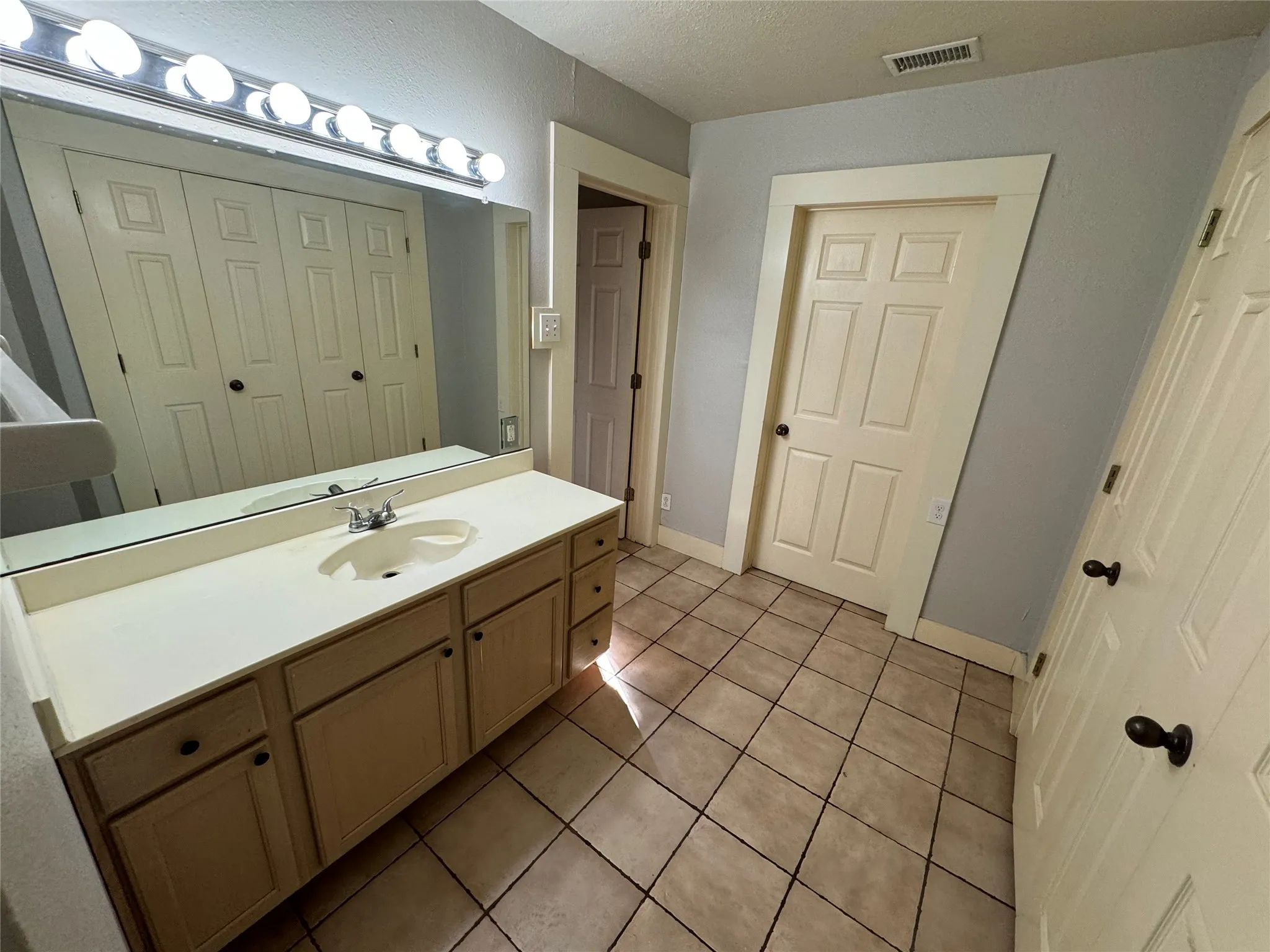 Bathroom with vanity, a textured ceiling, and tile patterned flooring