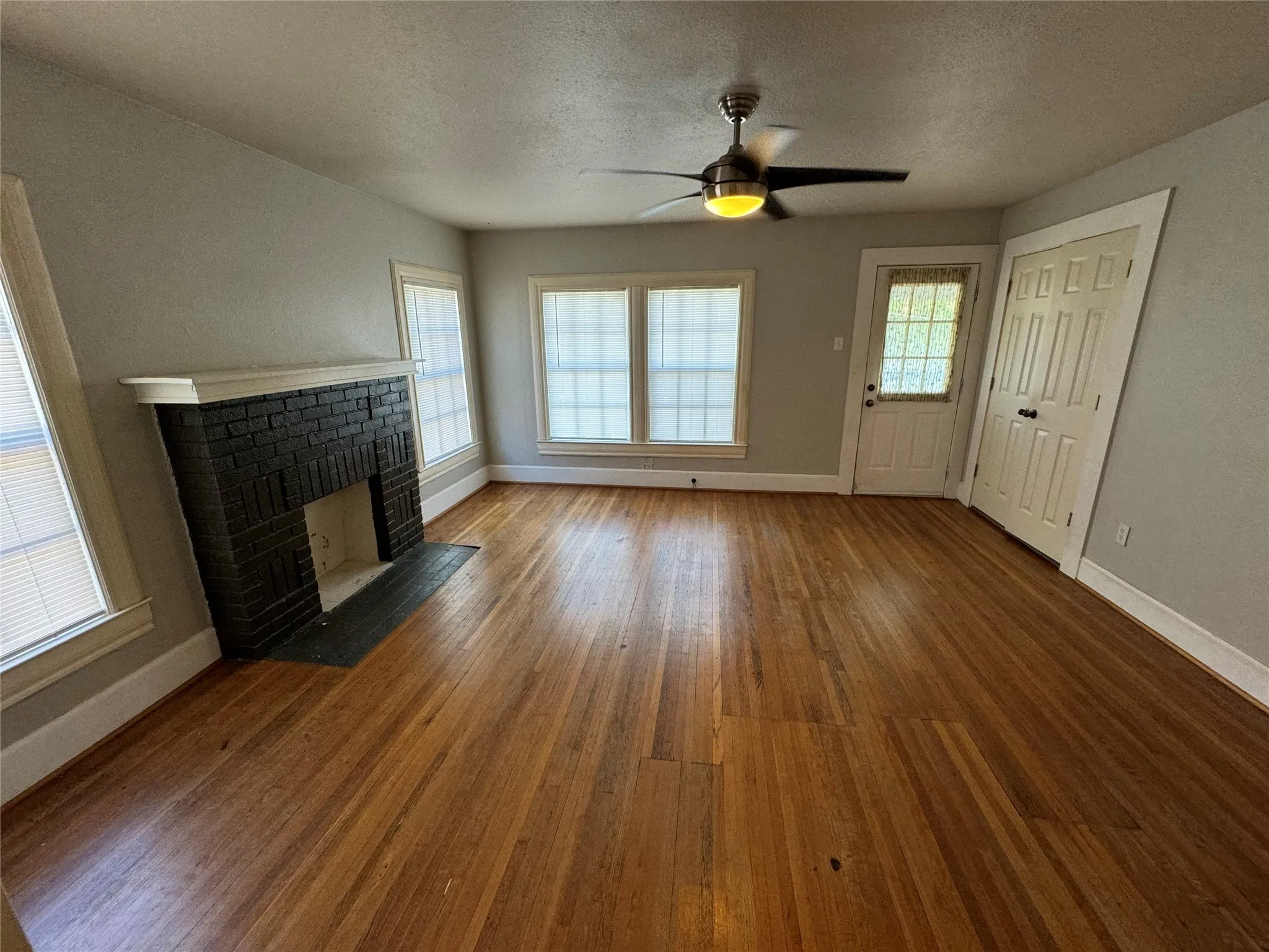 Unfurnished living room featuring a textured ceiling, ceiling fan, hardwood / wood-style flooring, and a fireplace