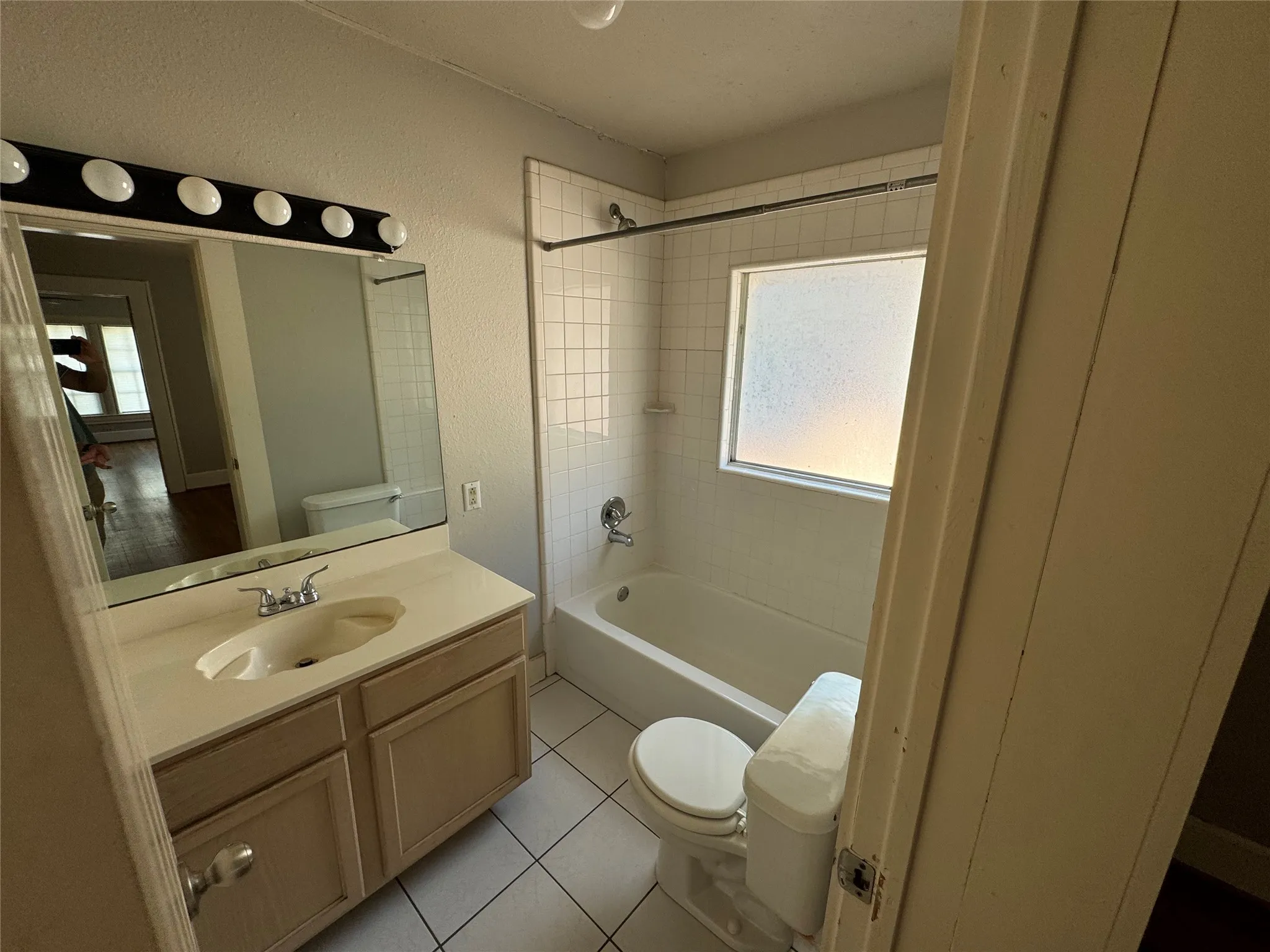 Full bathroom featuring vanity, toilet, tiled shower / bath combo, and a healthy amount of sunlight