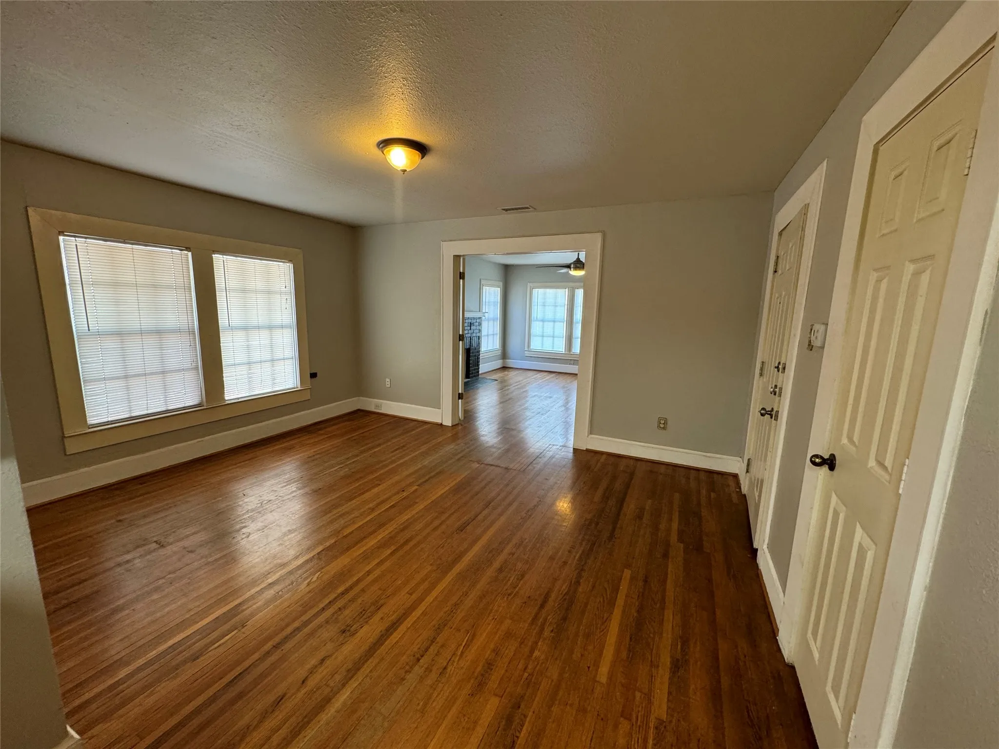 Unfurnished room featuring a textured ceiling, a wealth of natural light, ceiling fan, and dark hardwood / wood-style floors
