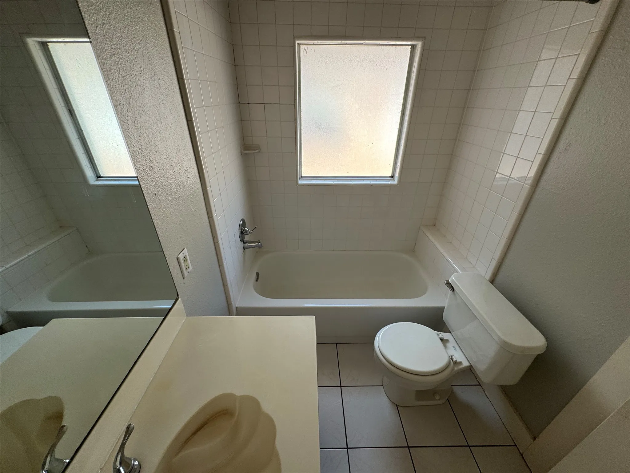 Full bathroom with plenty of natural light, toilet, tiled shower / bath combo, and tile patterned floors