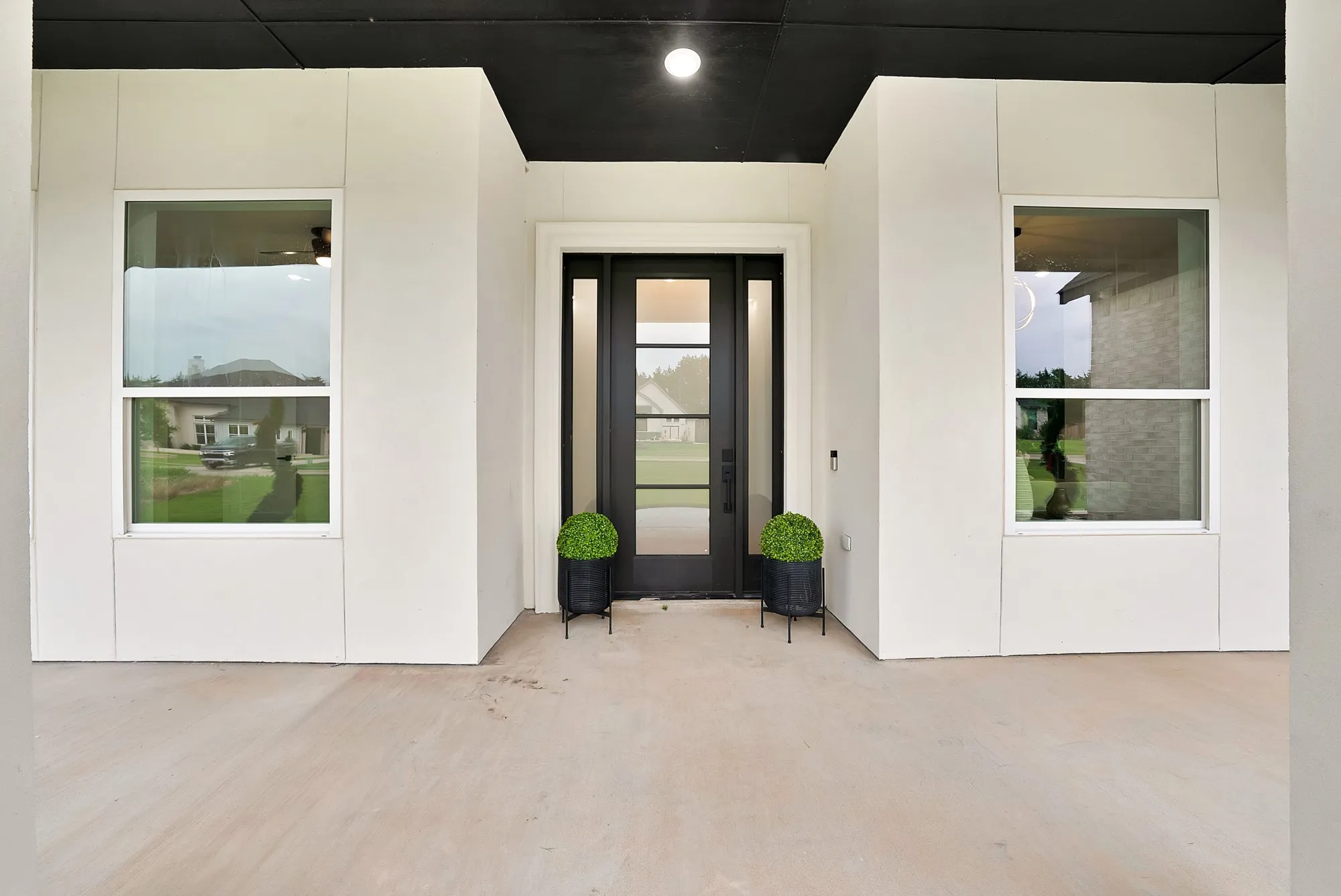 Covered front porch with a dark ceiling accent, vertical white paneling, and a full-light entry door