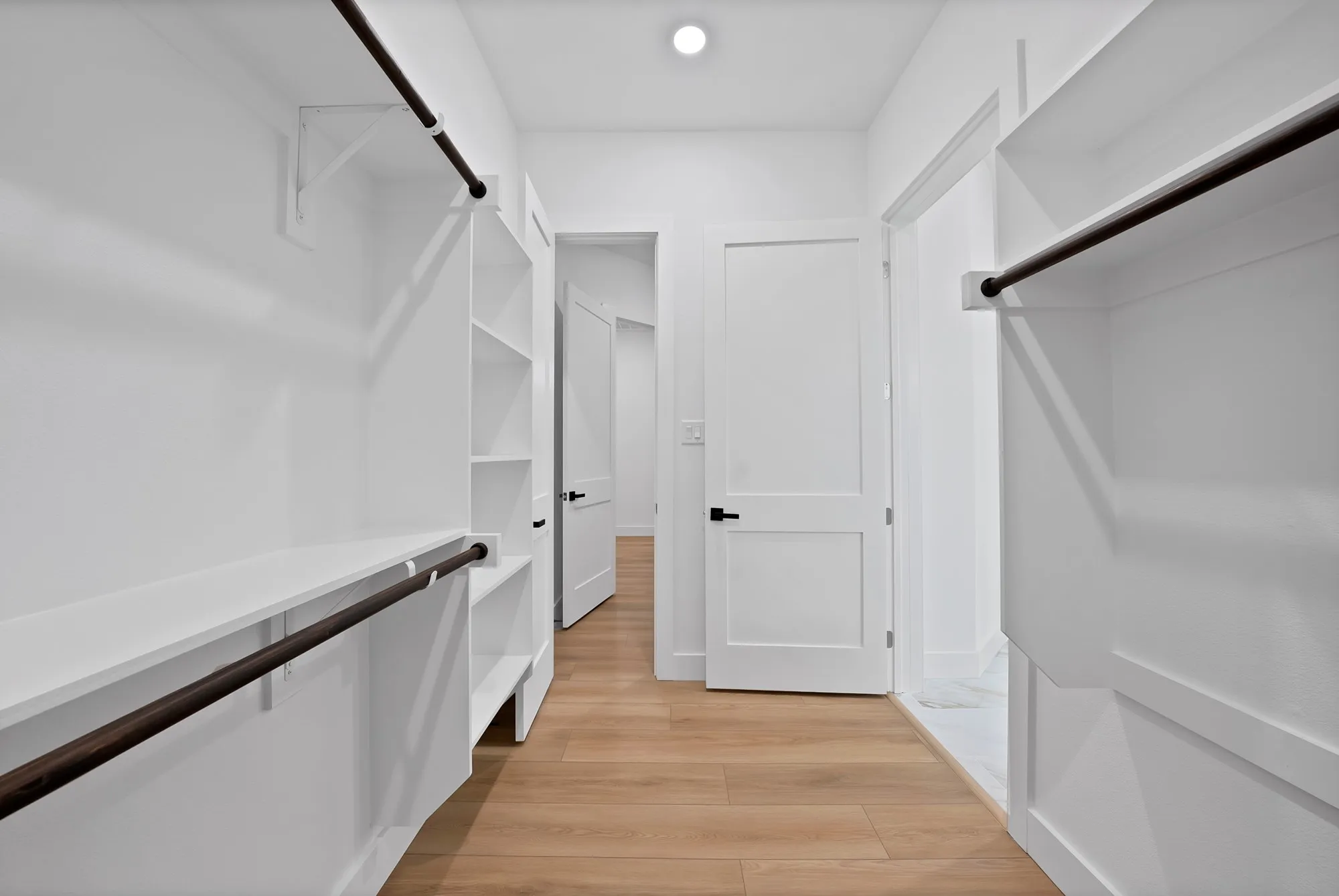 Built-in closet shelving and hanging rods, wood-finish flooring, white paneled doors, and recessed lighting