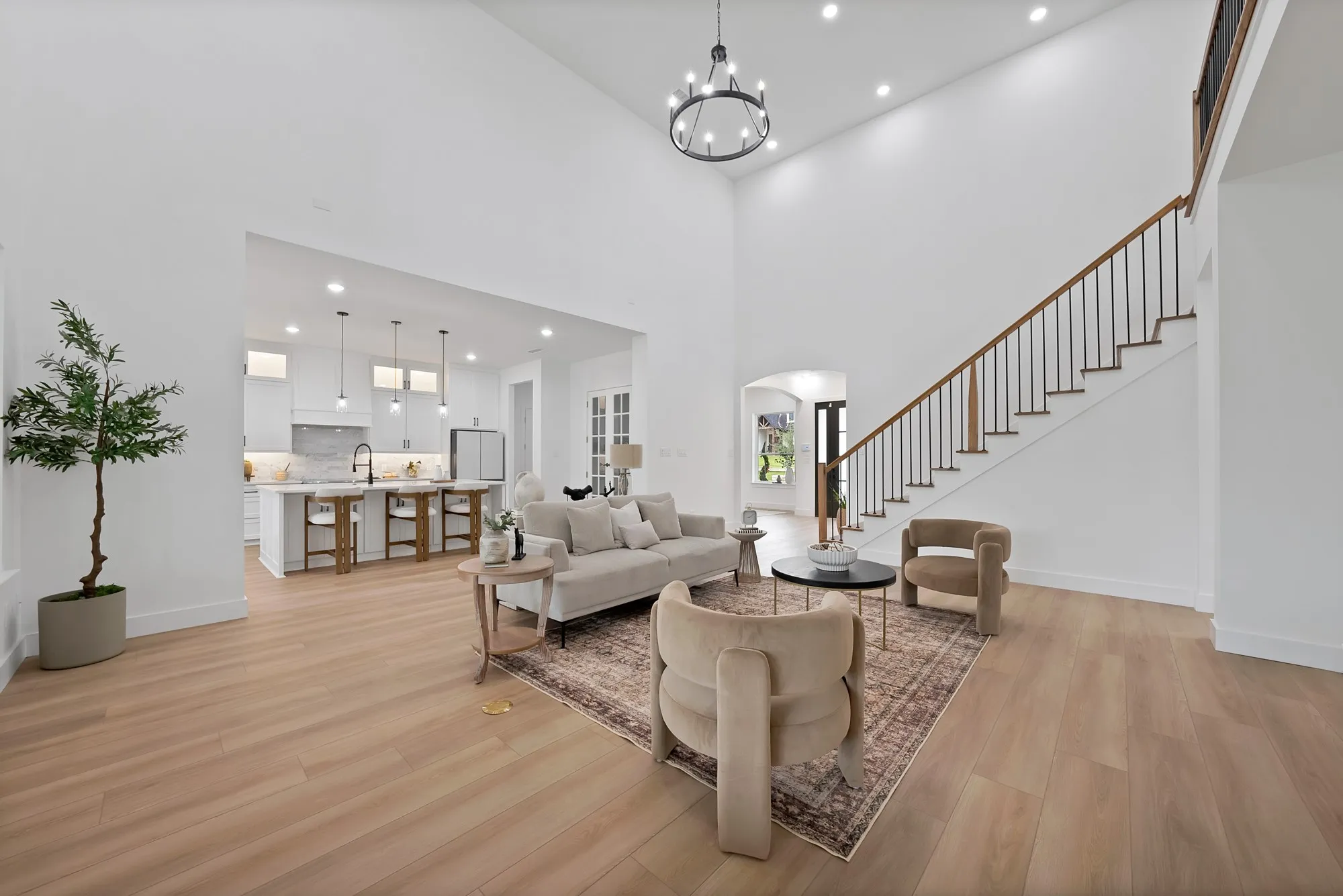 Two-story living area with wood-finish flooring, a contemporary chandelier, and recessed lighting