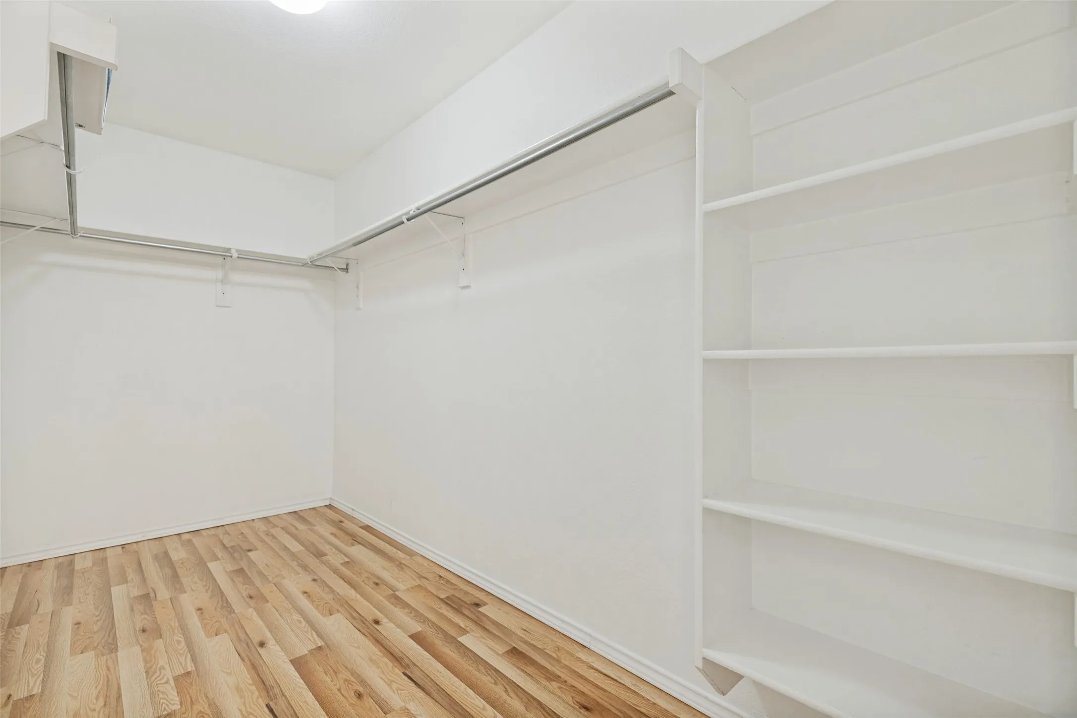 Wood-finish flooring, built-in shelving, white walls, and overhead lighting